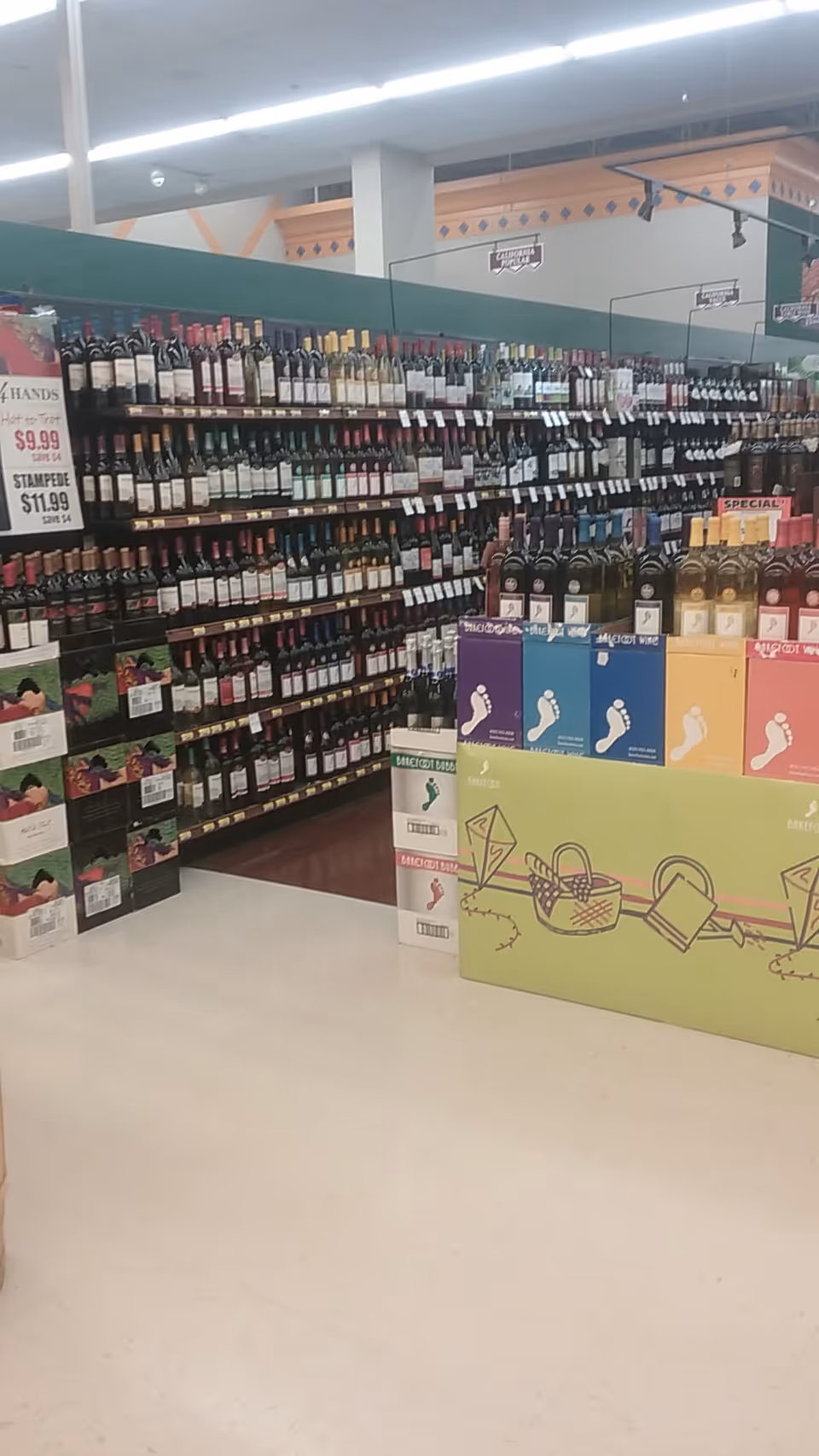 Inside Discount Drug Mart, a long aisle of liquor shelves filled with bottles.