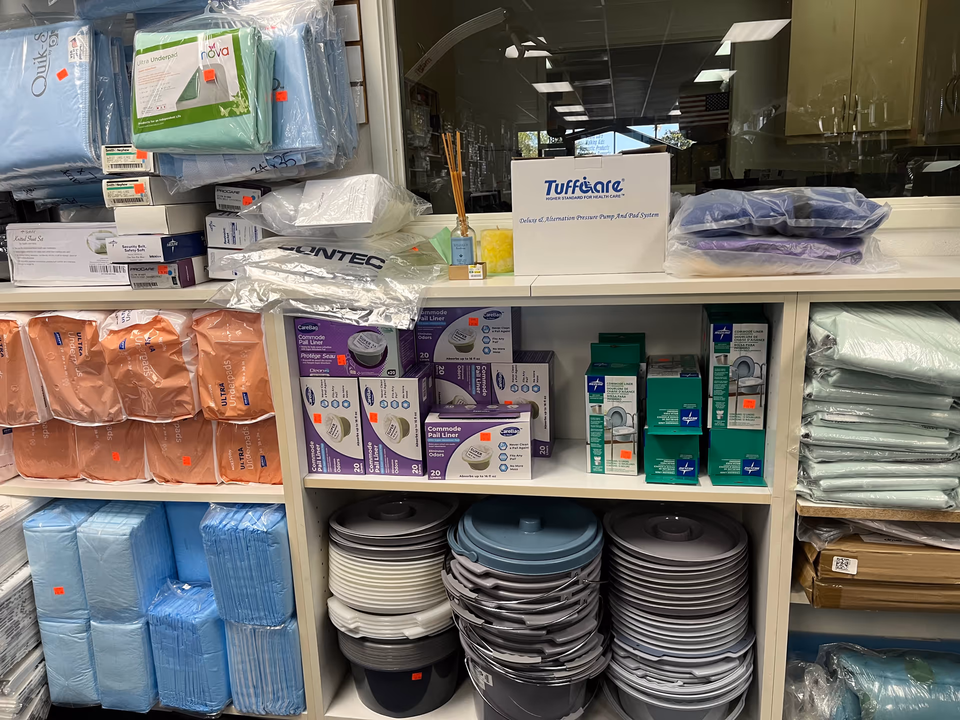 Shelves stocked with medical supplies, pads, and containers in a clinic storage area.