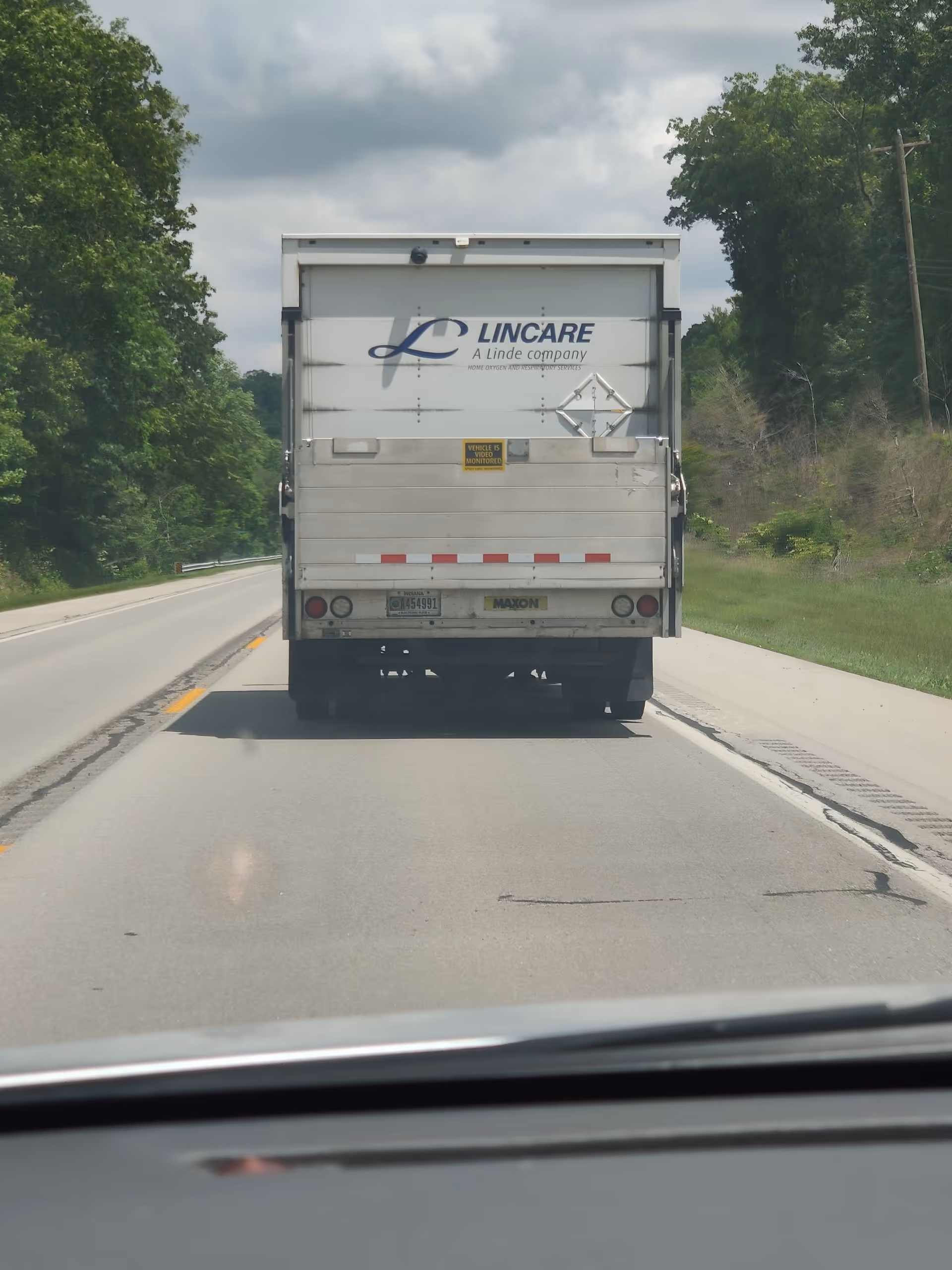 Rear view of a Lincare truck on a rural road with trees on both sides.