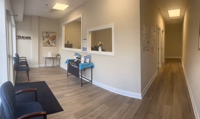 Interior reception area with chairs, a welcome sign, and a service desk.