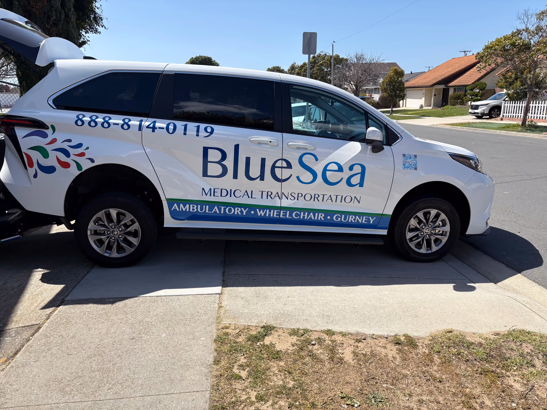 White BlueSea medical transport van parked on a suburban street with houses