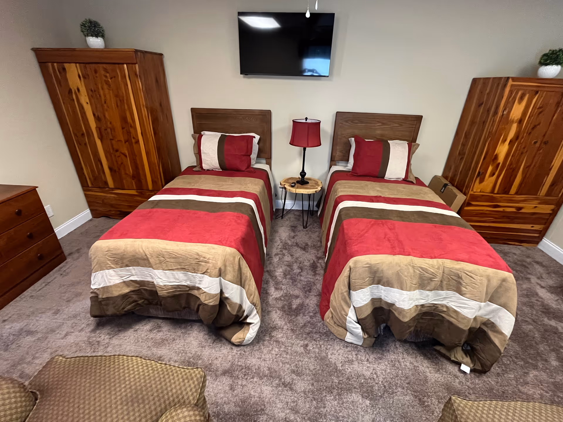 Two twin beds with matching bedding and wooden wardrobes fill a shared bedroom.
