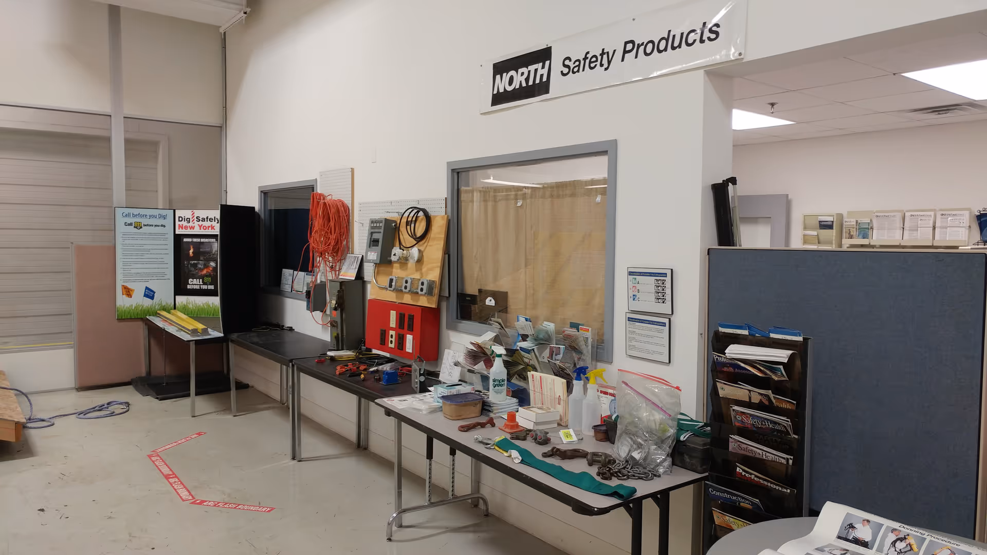 Interior workshop area with safety equipment displays, tools, and a North Safety Products sign.