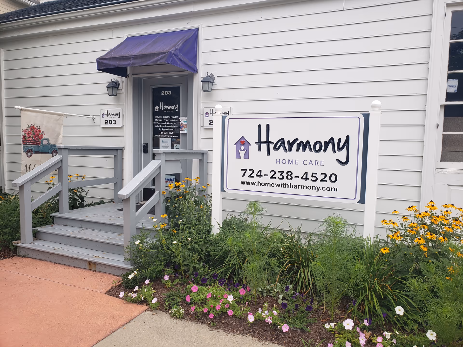 Exterior view of Harmony Home Care building with front steps, signage, and blooming flowers.