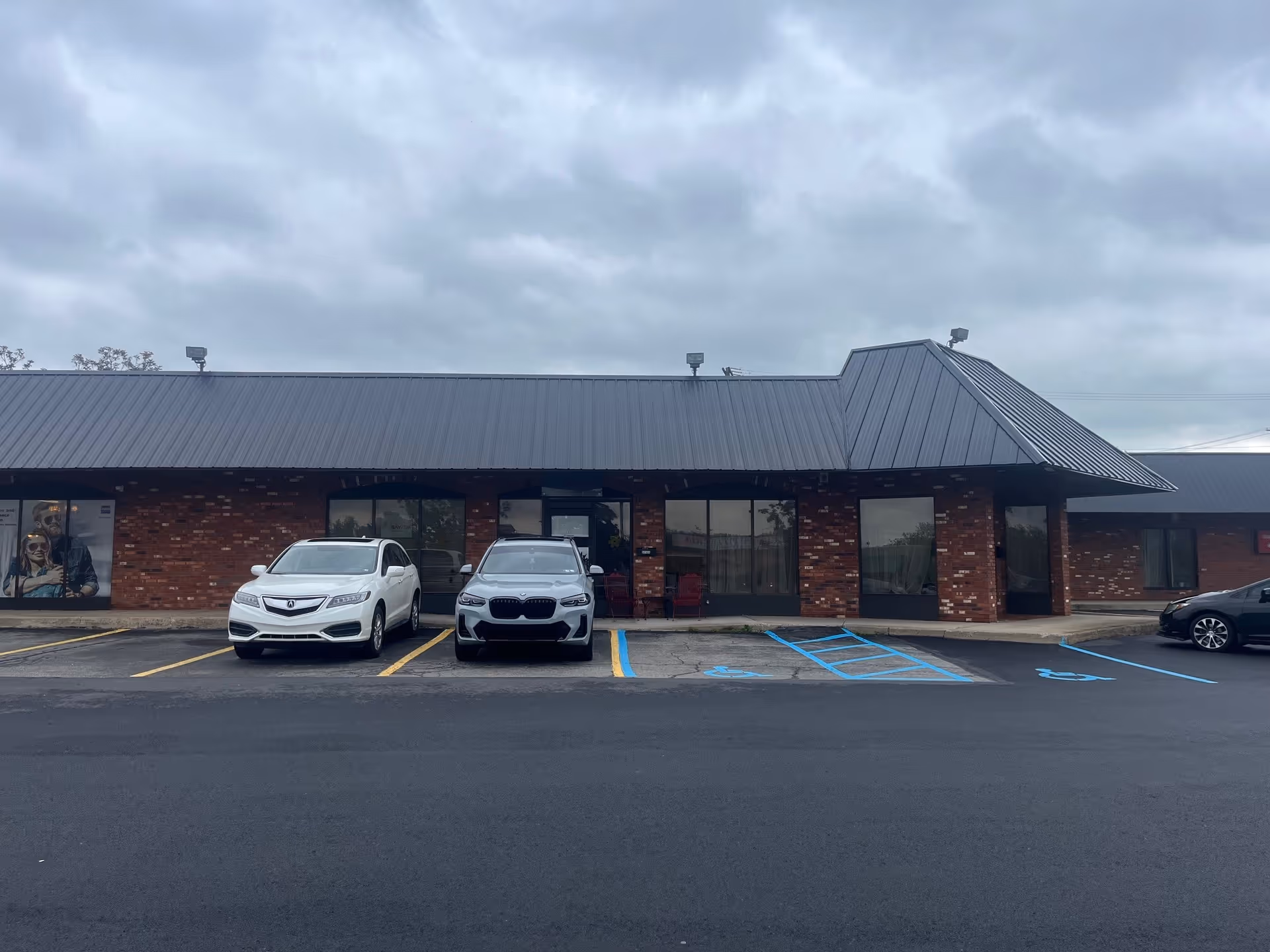 Brick senior living facility exterior with parked cars and blue handicap spaces.