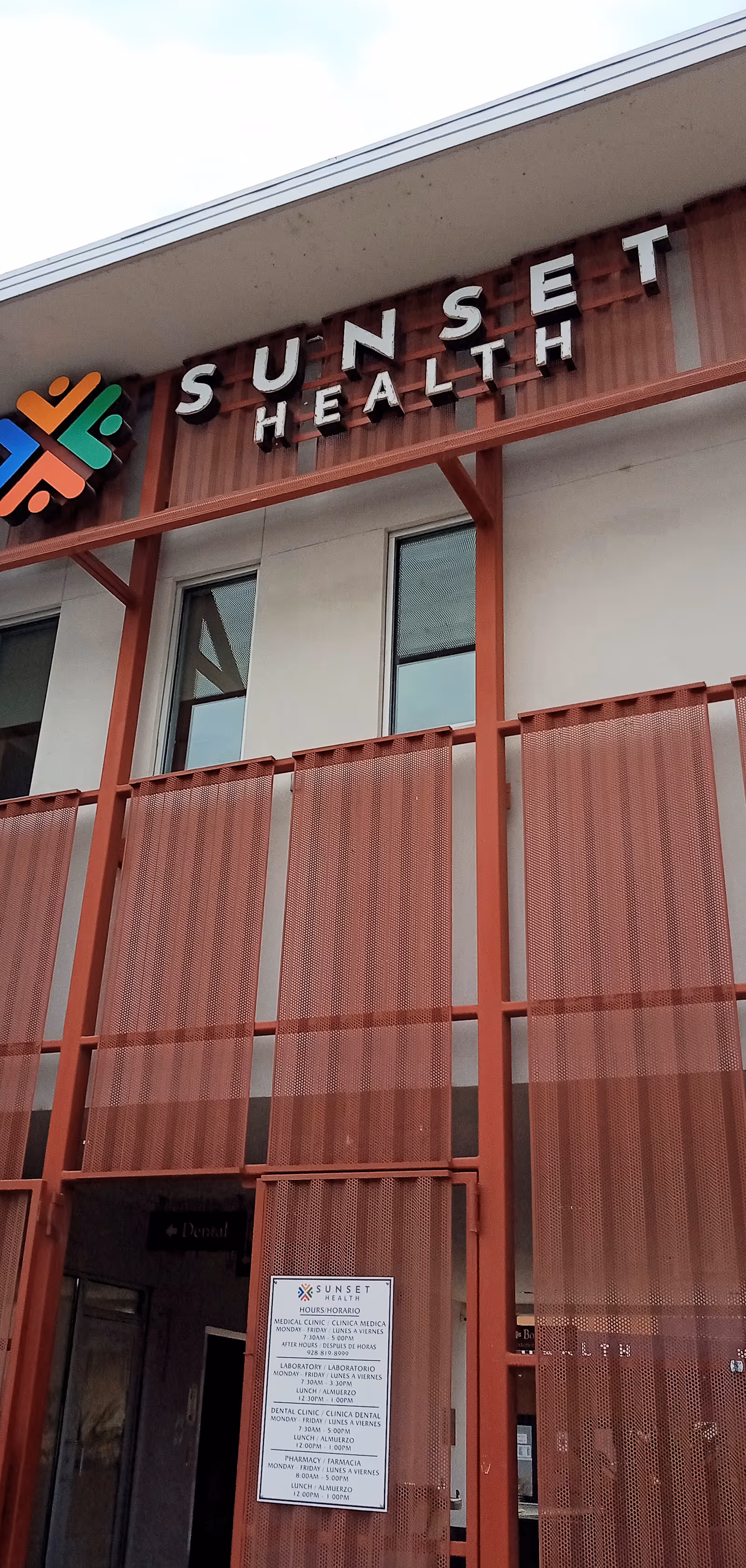 Exterior facade of Sunset Health building with red metal panels and signage.