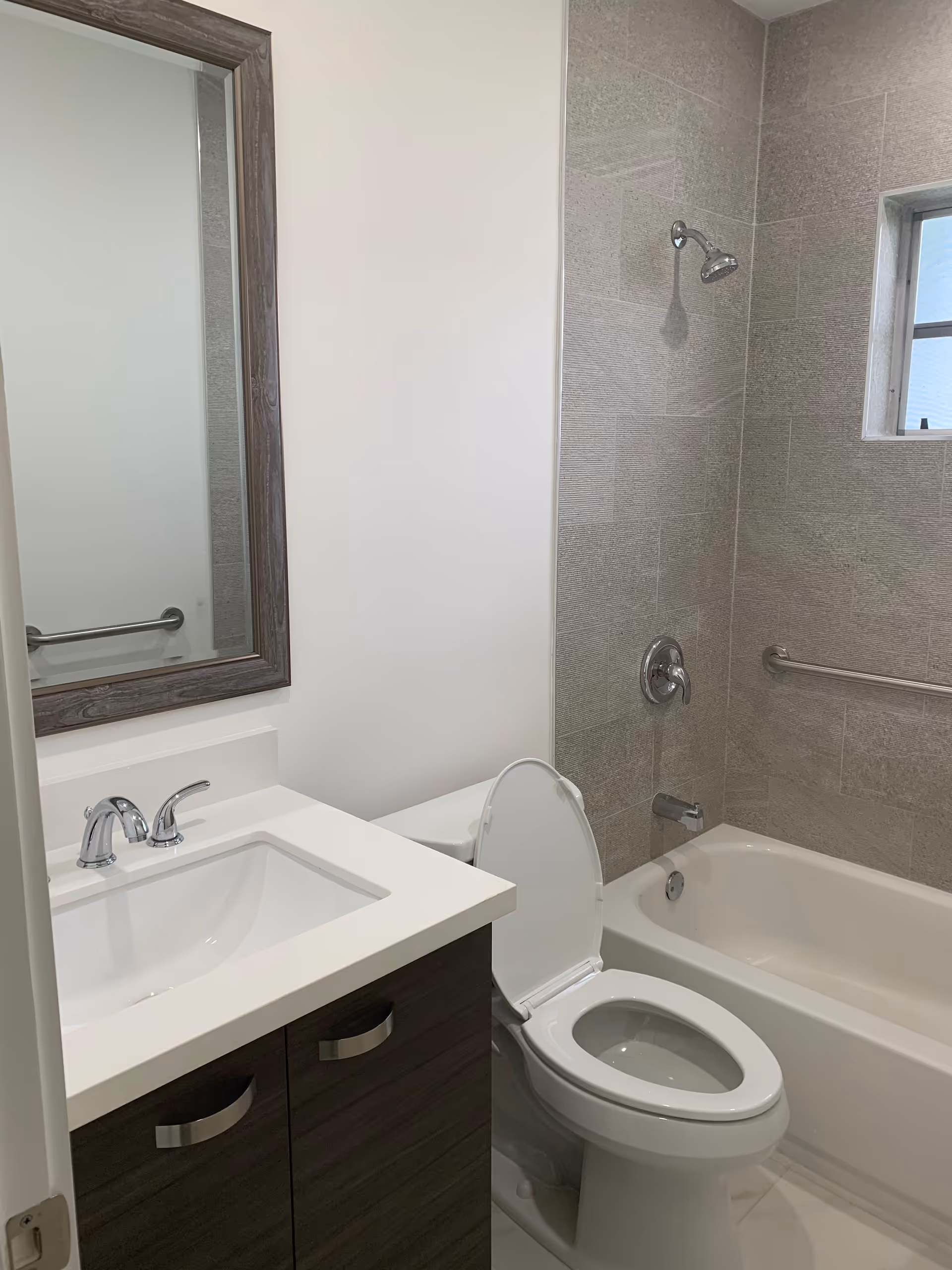 Clean bathroom with sink, mirror, toilet, and tiled shower area.