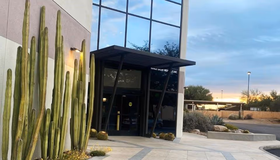 Exterior view of Cornerstone Caregiving facility entrance with tall cacti and glass doors.