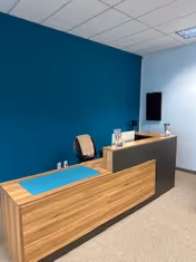 Reception desk in a modern interior with blue accent wall and ceiling tiles.