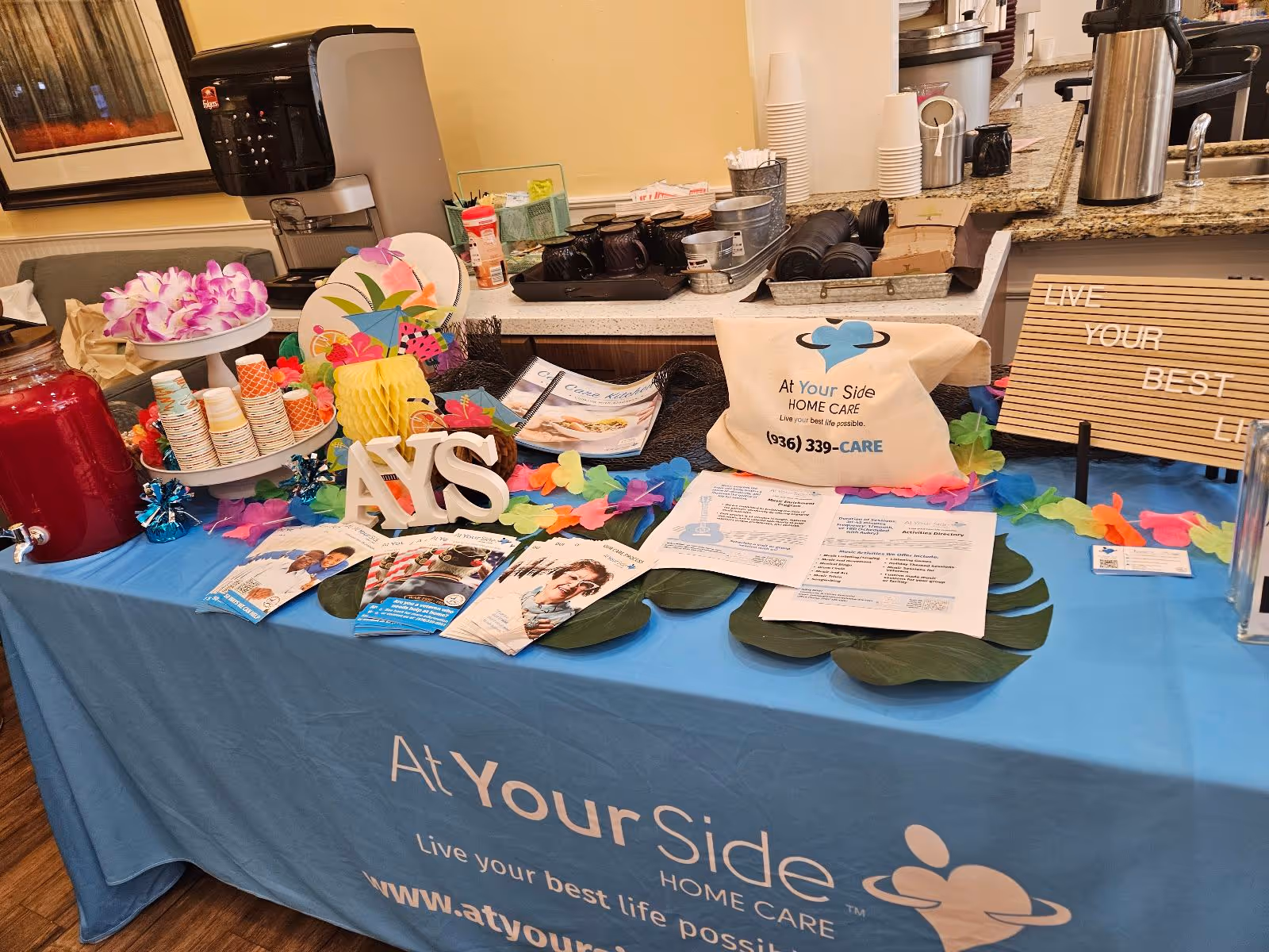 Promotional display for At Your Side Home Care on a blue tablecloth inside a facility.