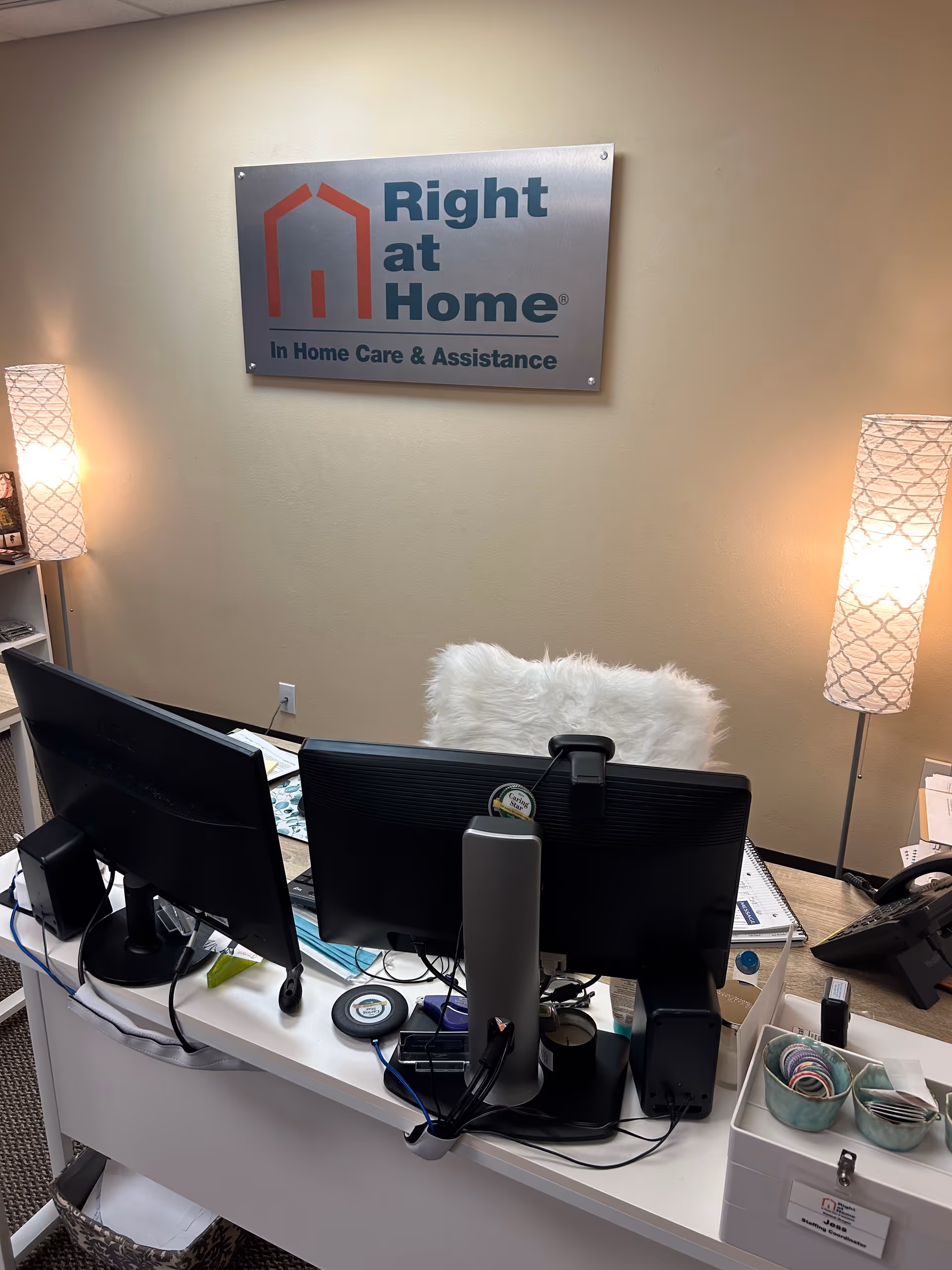 Reception desk with dual monitors and a Right at Home sign on the wall.