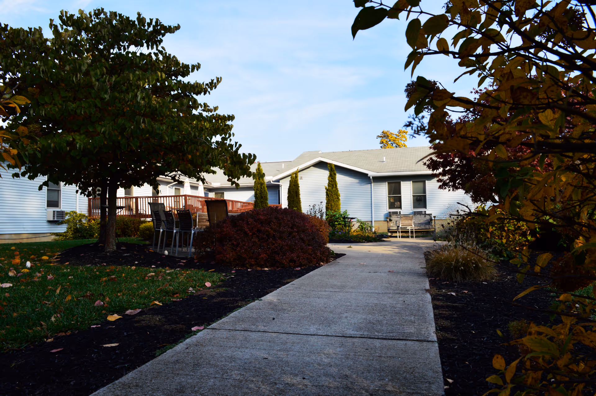 Exterior of a single-story senior living facility with a walkway and outdoor seating area.