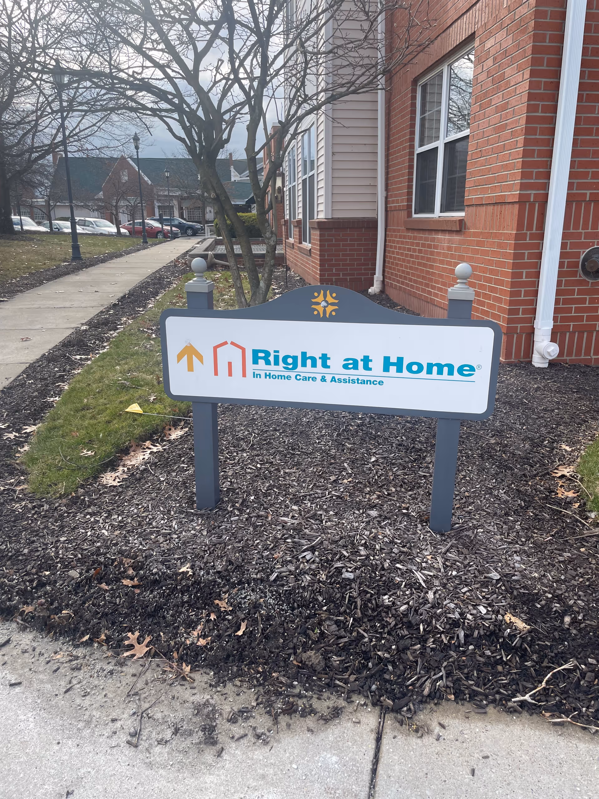 Outdoor sign for Right at Home senior care near a brick building entrance.