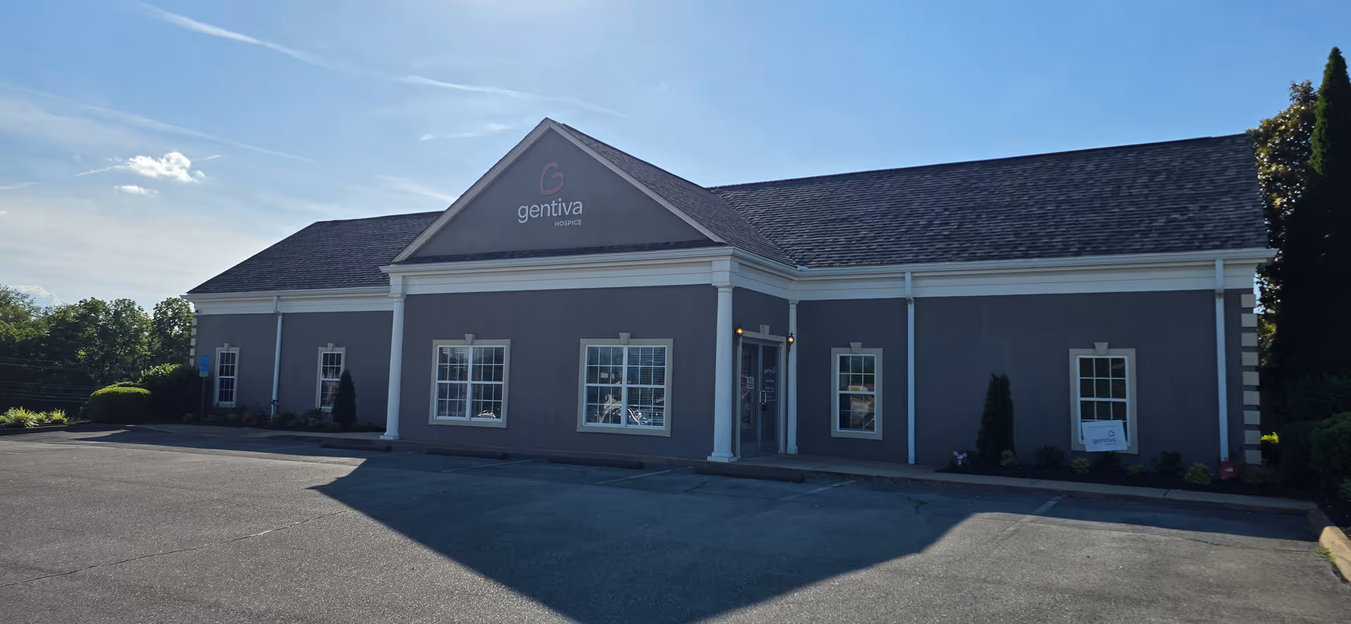 Grey medical facility building with pitched roof and Gentiva Hospice sign at front.