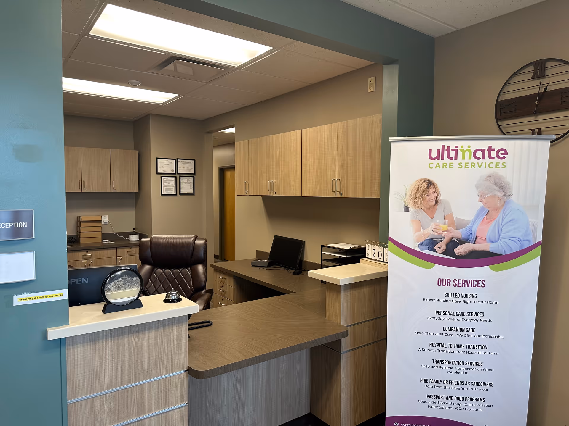Reception desk in a modern facility lobby with cabinets and Ultimate Care Services banner.
