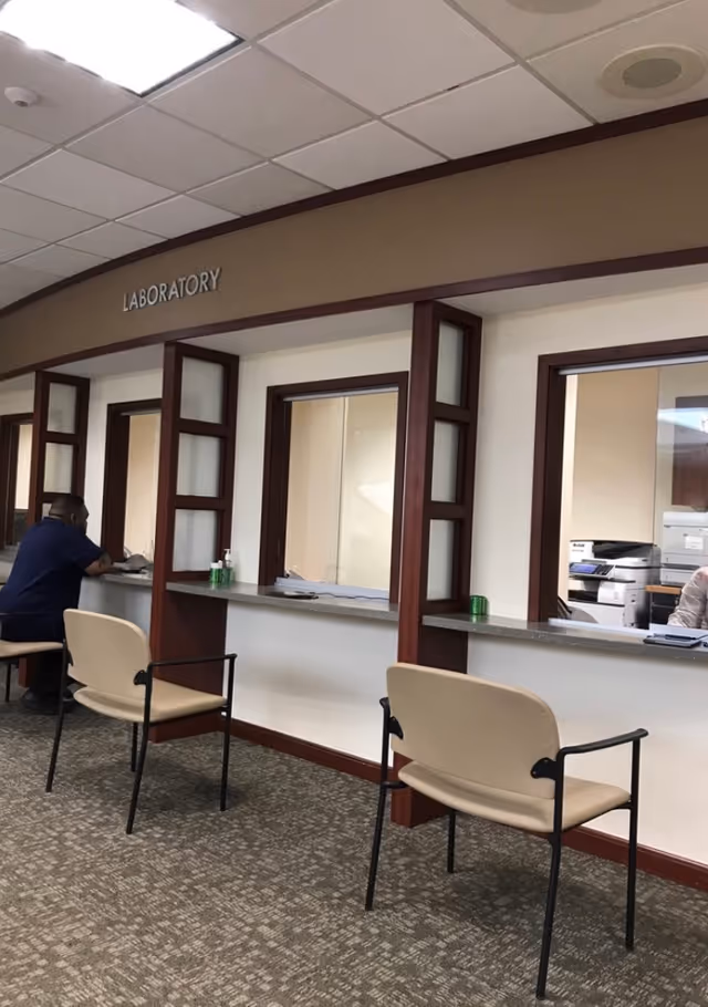 Medical laboratory reception area with service windows and seating.