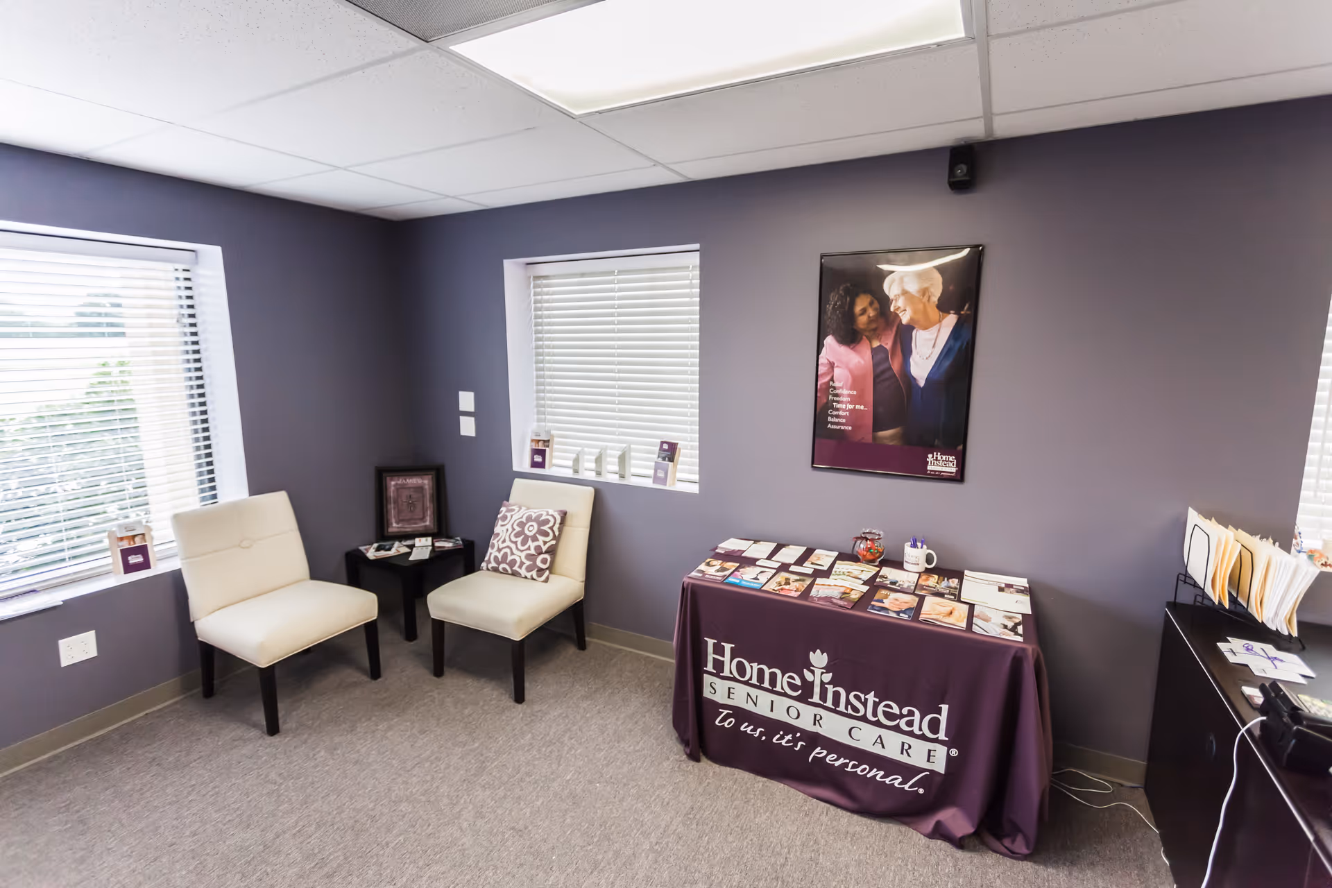 Waiting area with two white chairs, a purple table cover, and brochures.