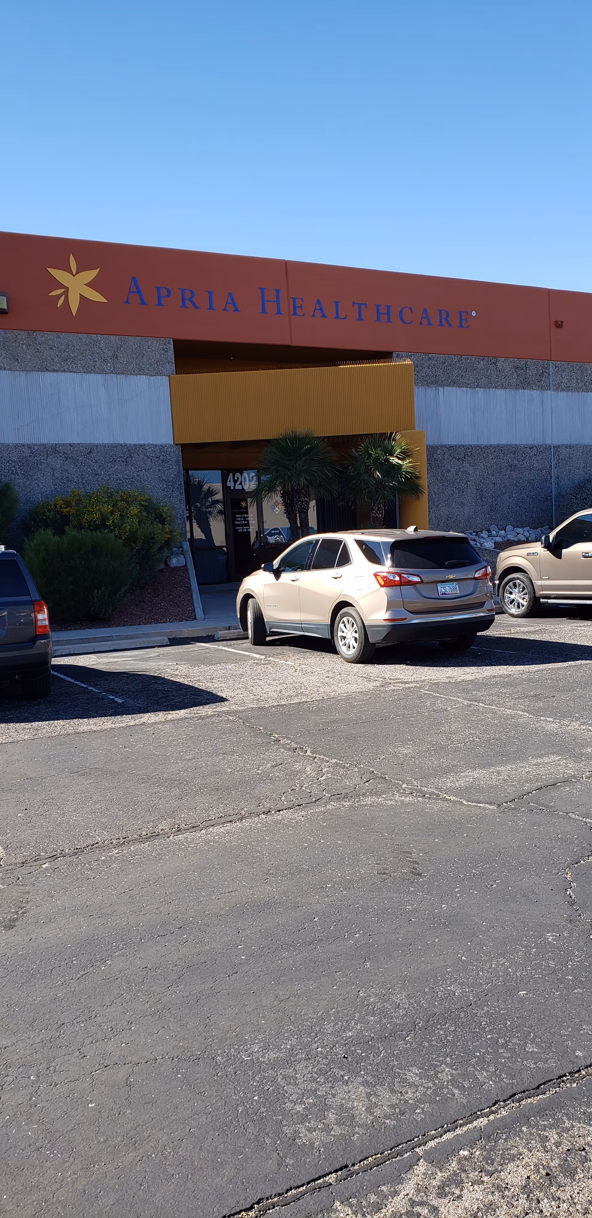 Apria Healthcare building exterior with parking lot and entrance beneath a red sign.