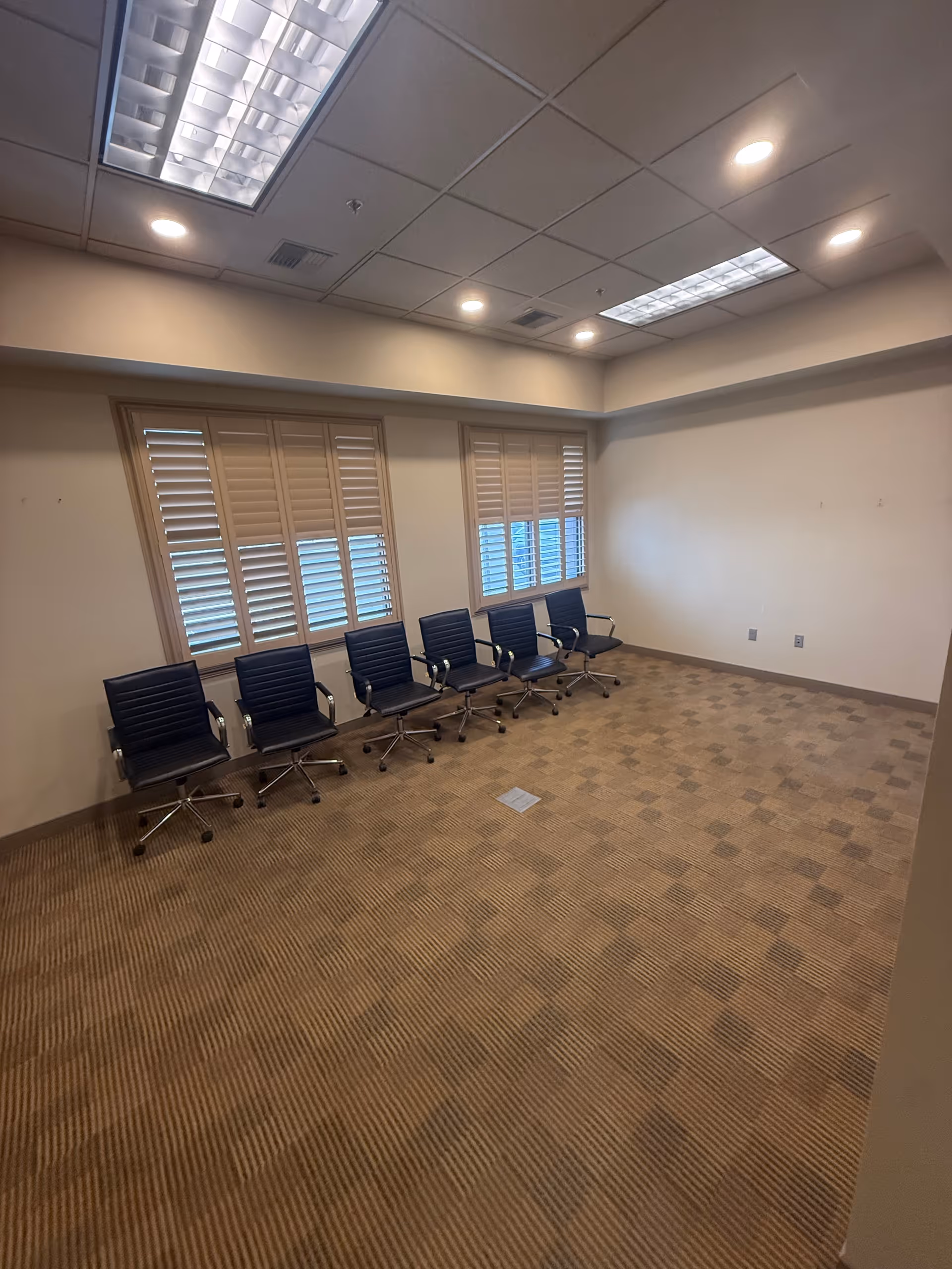 Empty interior room in a senior facility with rowed black chairs.