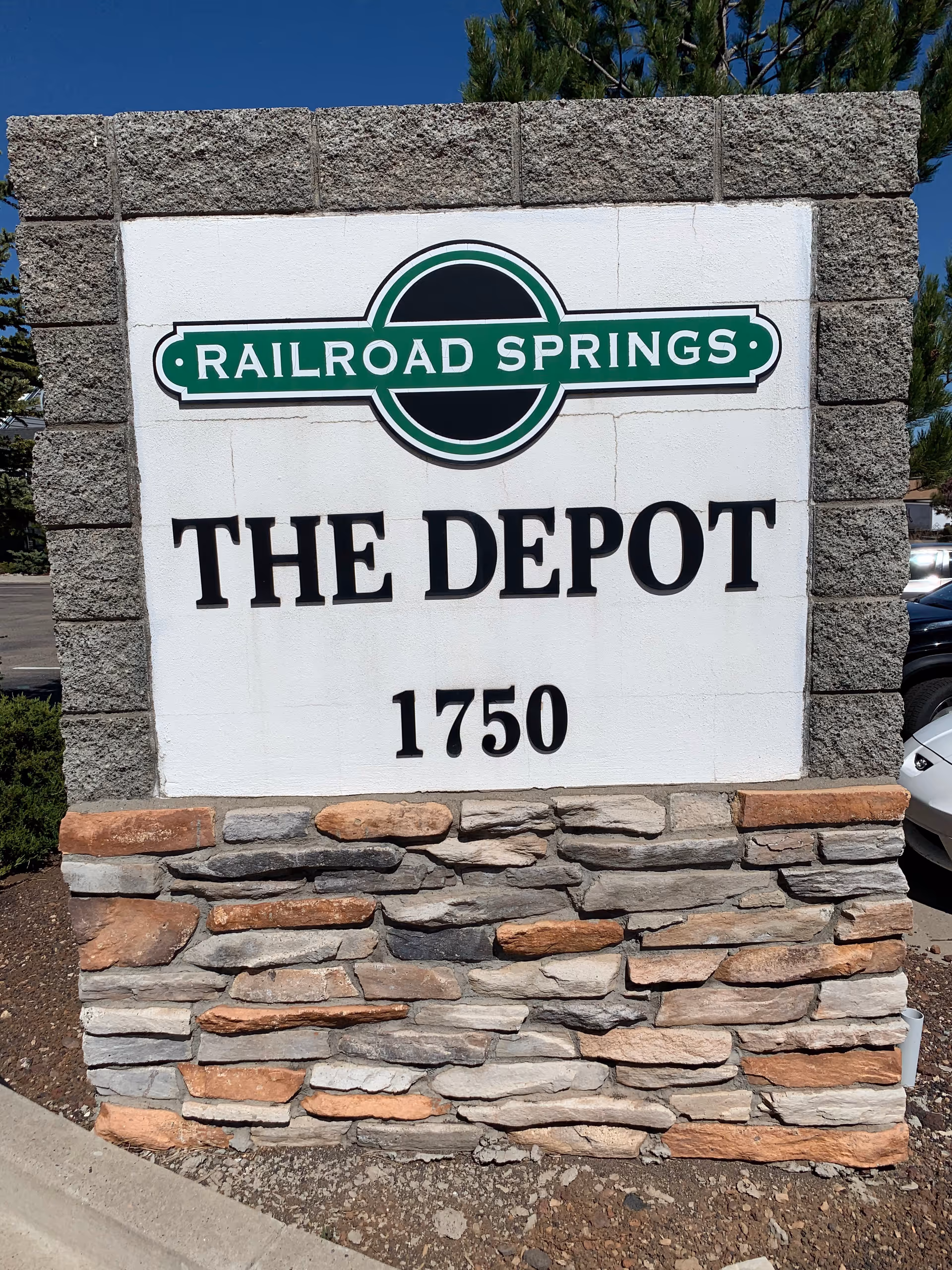 Stone sign reading Railroad Springs The Depot, 1750, with a stacked-stone base outdoors.