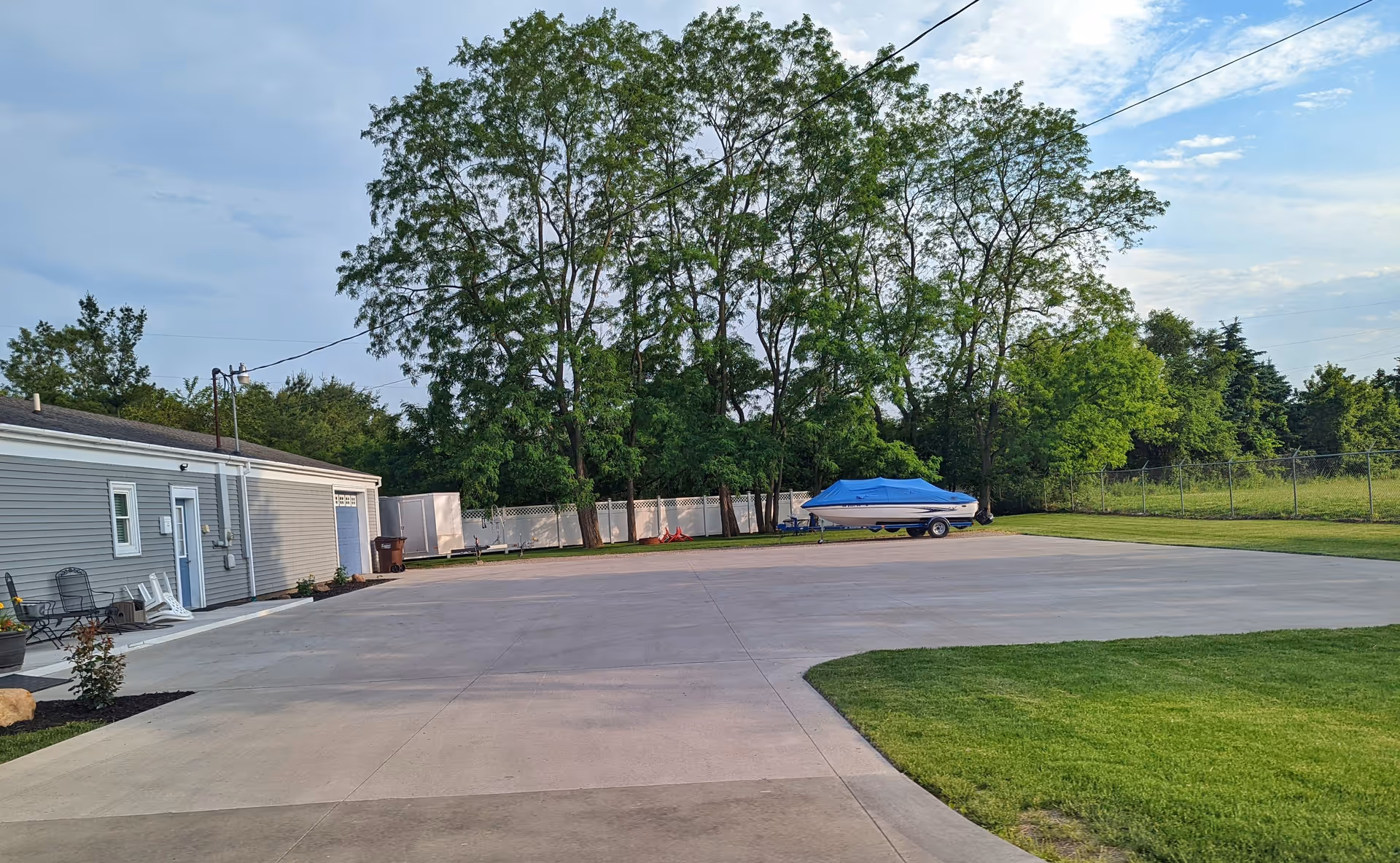 Exterior view of a Comfort Keepers facility: gray building, expansive lot, and tall trees.