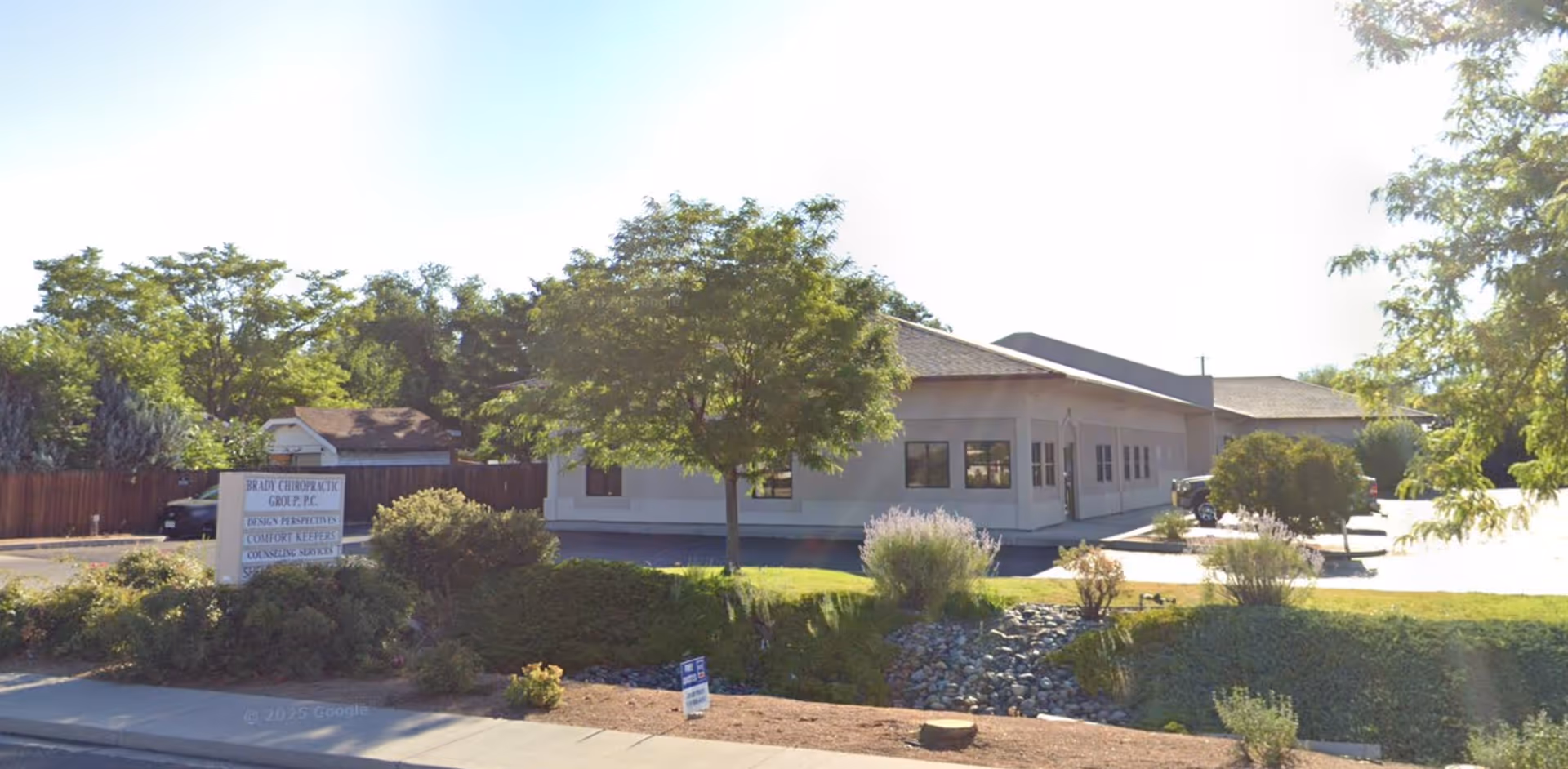 Exterior view of Comfort Keepers Home Care facility with trees, shrubs, and parking.