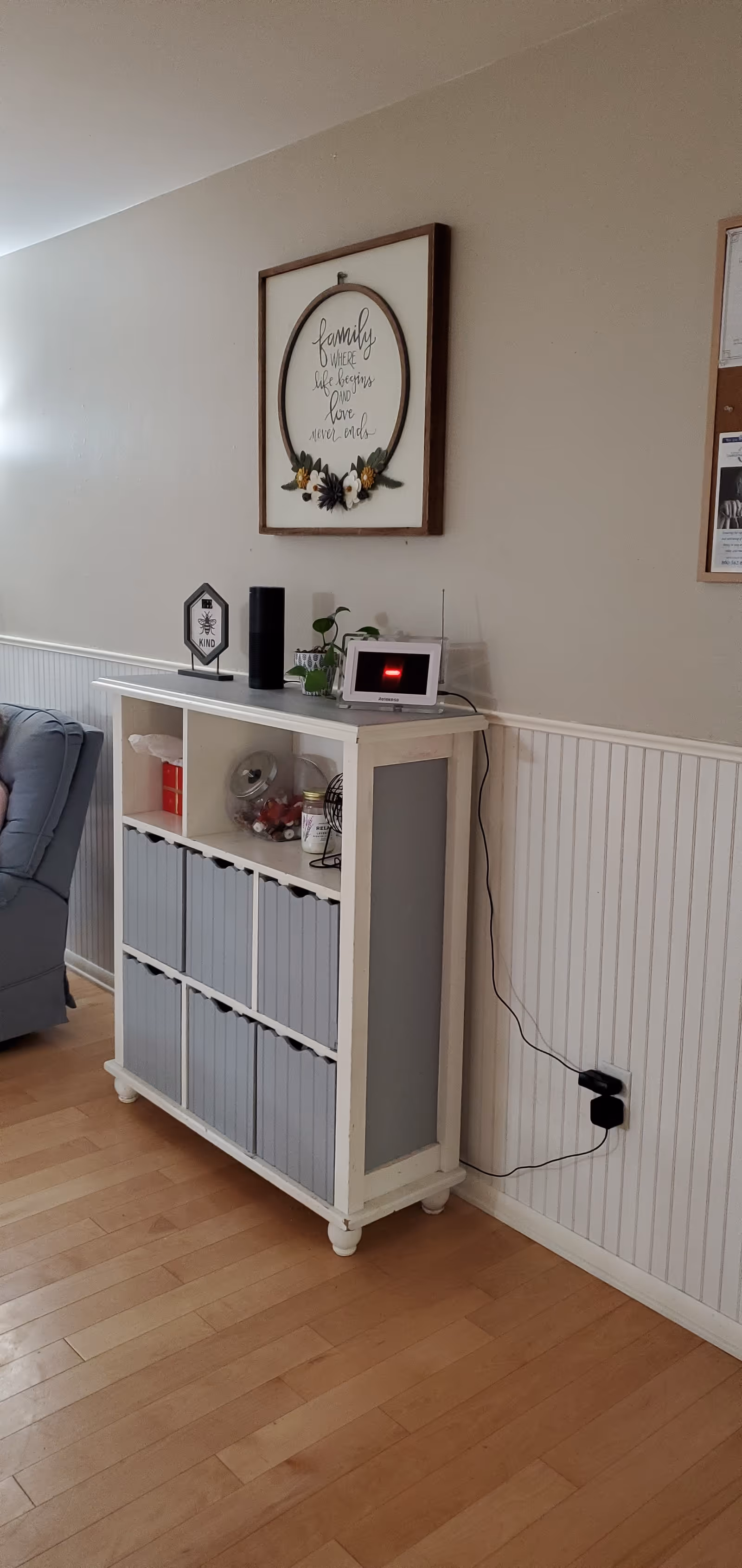White console with storage bins and decor against beadboard-walled living room interior.