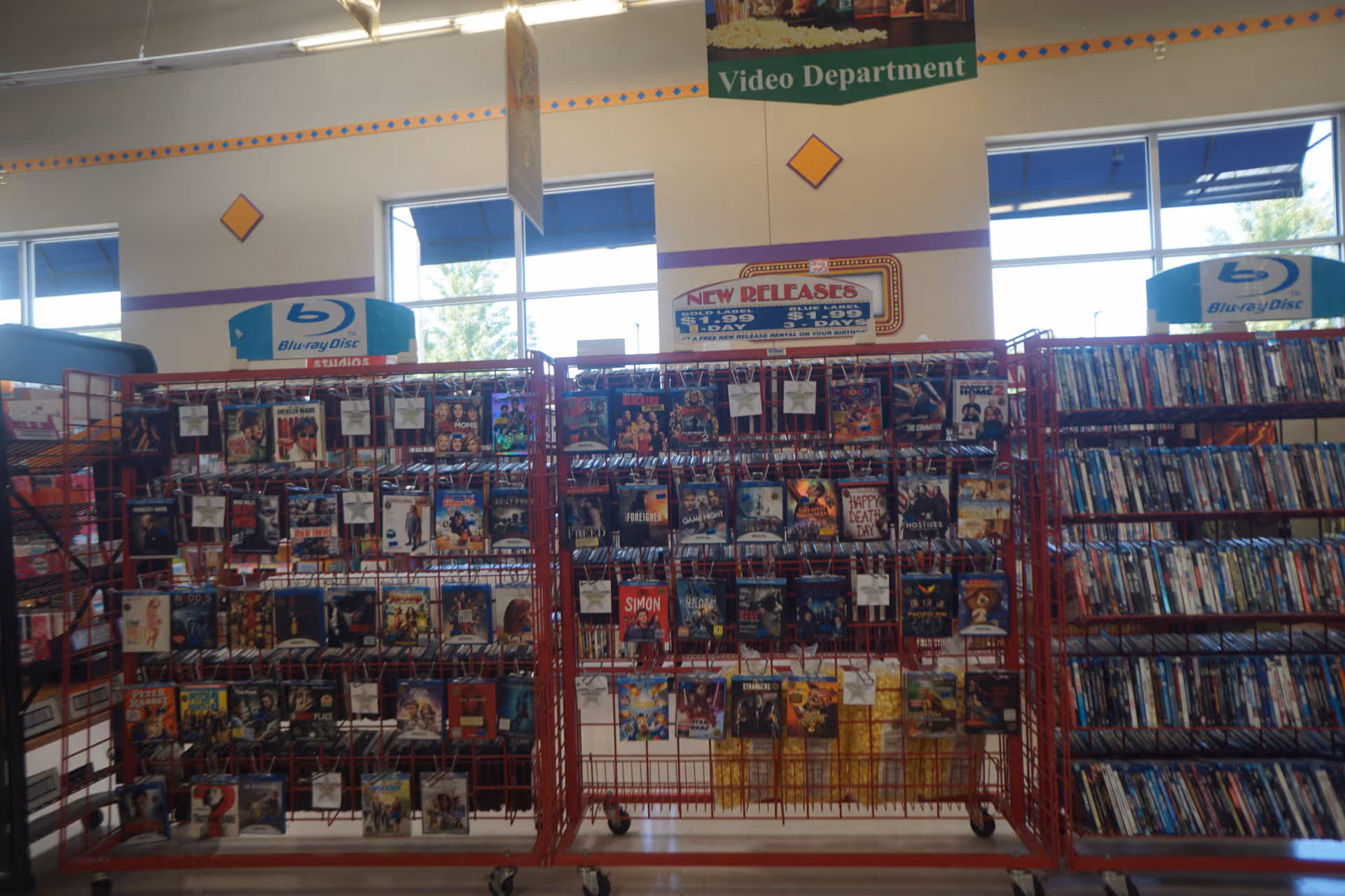 Inside Discount Drug Mart, red metal racks display DVDs and Blu-rays in the video department.