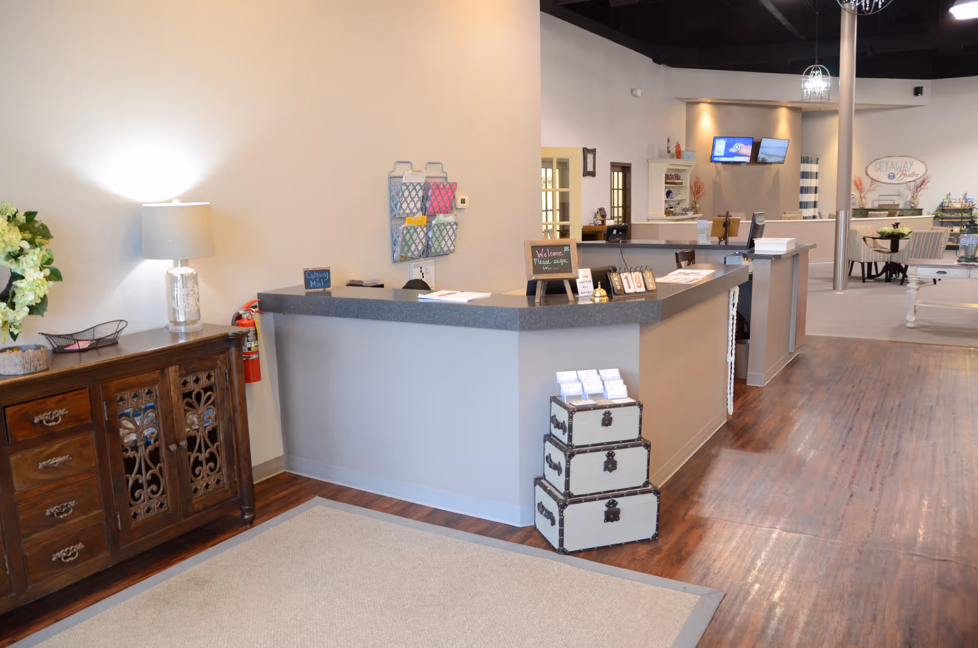 Reception desk in a bright lobby with a wooden cabinet and luggage display.