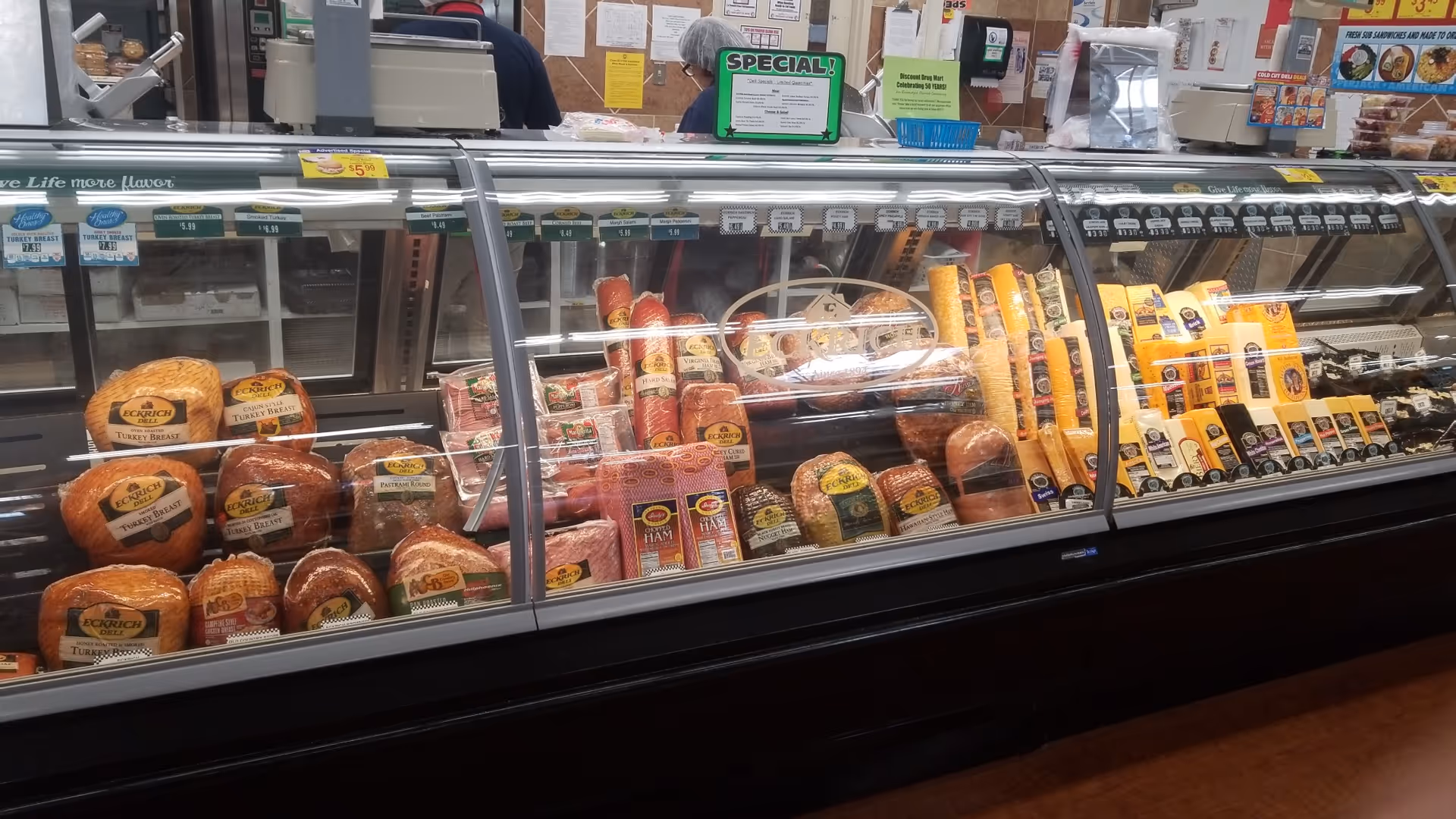 Deli counter at Discount Drug Mart with assorted meats and cheeses.