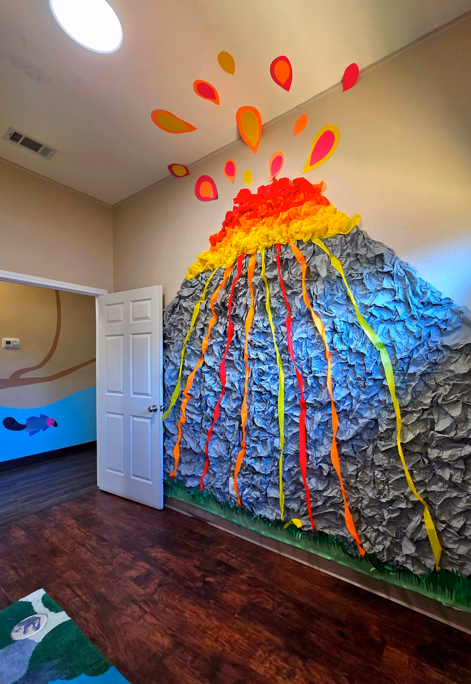 Interior hallway featuring a large crumpled blue paper hill with rainbow streamers.
