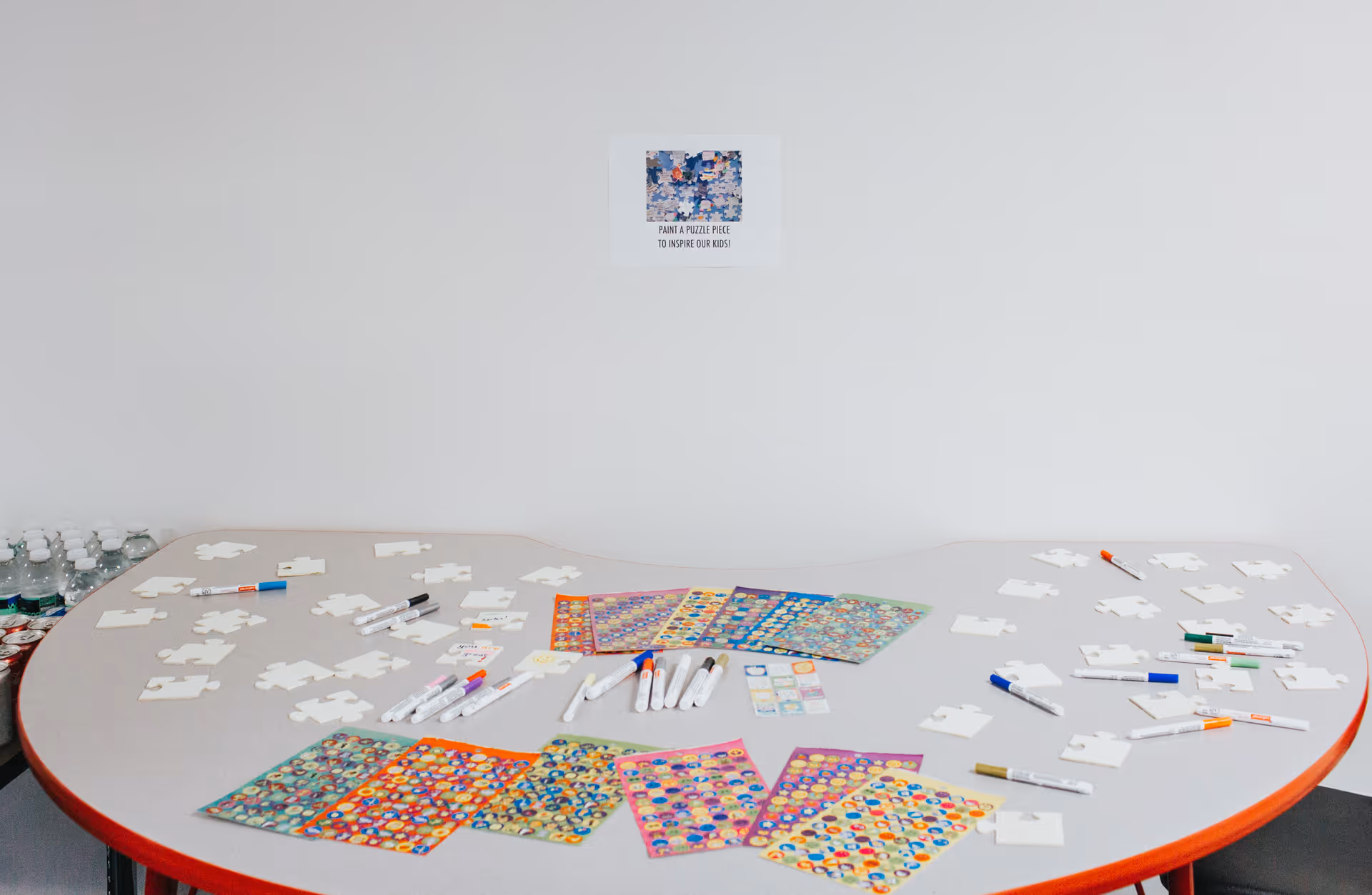 Round white table with puzzle pieces, markers, and boards in a bright activity room.