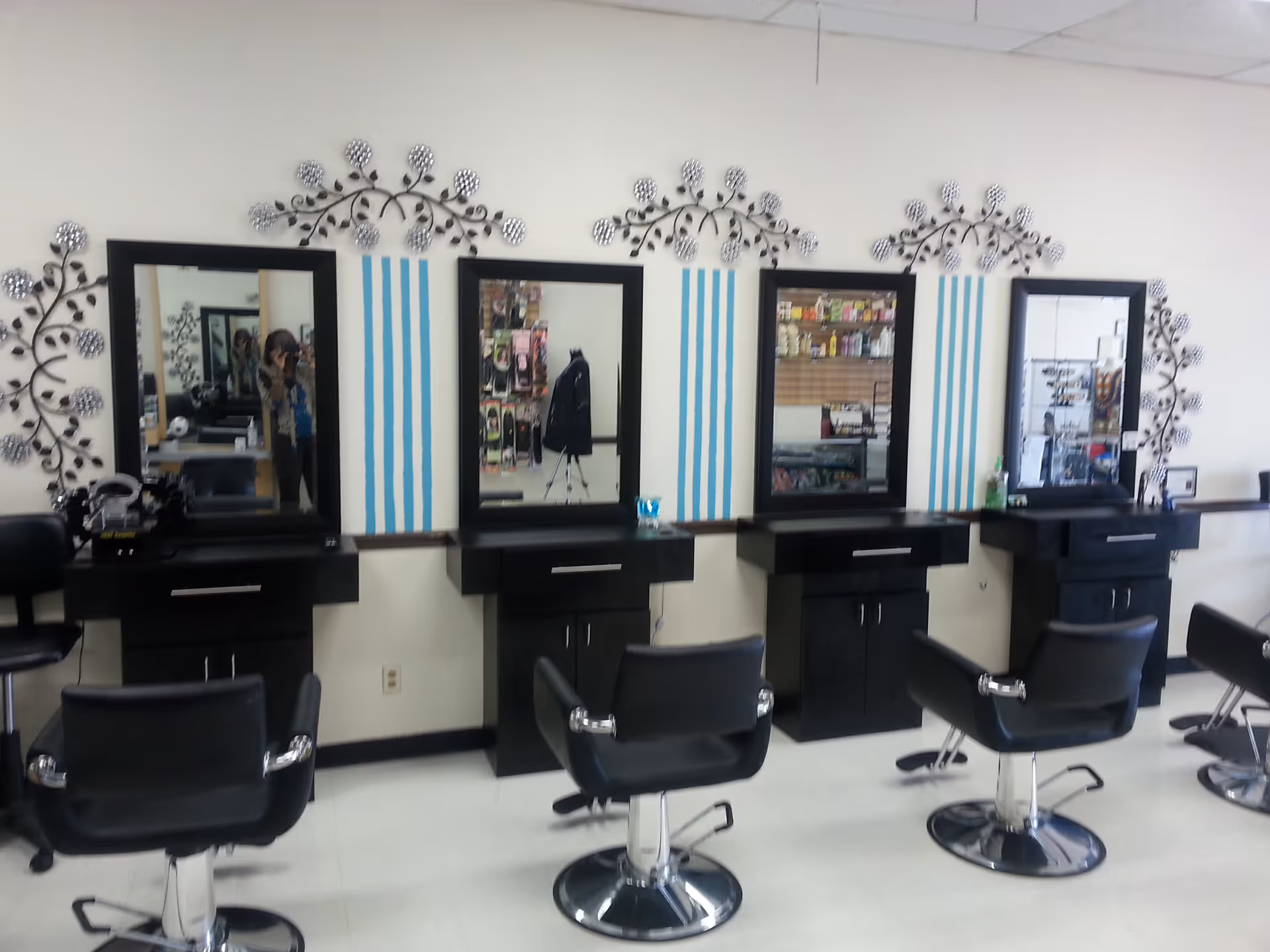 Row of black salon chairs and mirrors along a wall in a beauty salon.