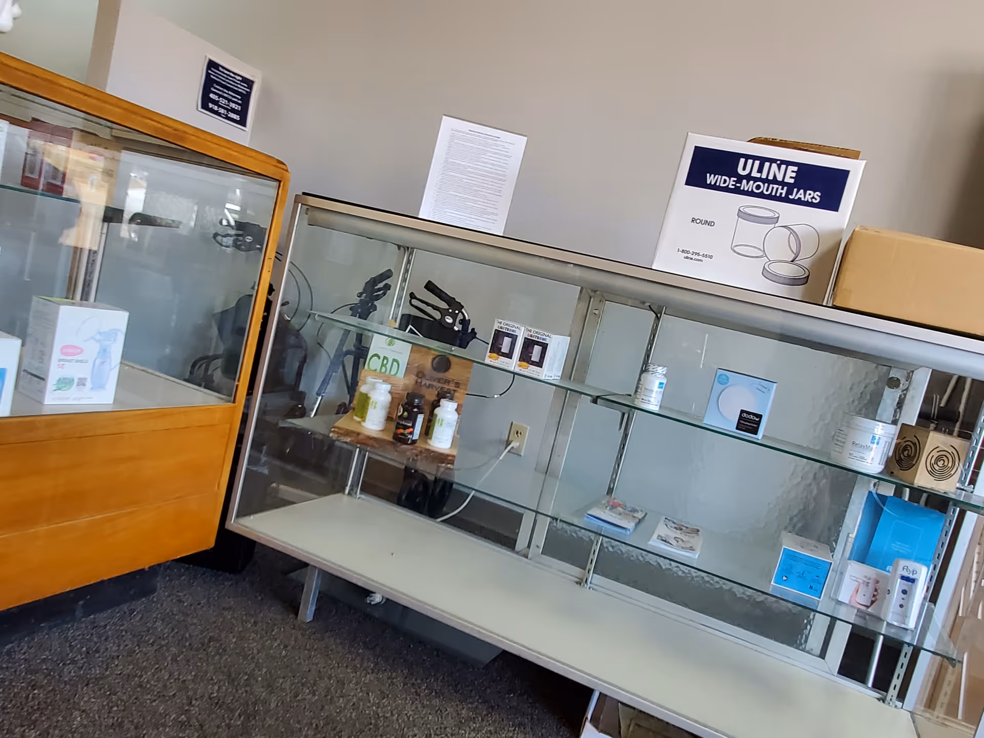 Interior of a medical facility with glass display case, shelves, and supplies.