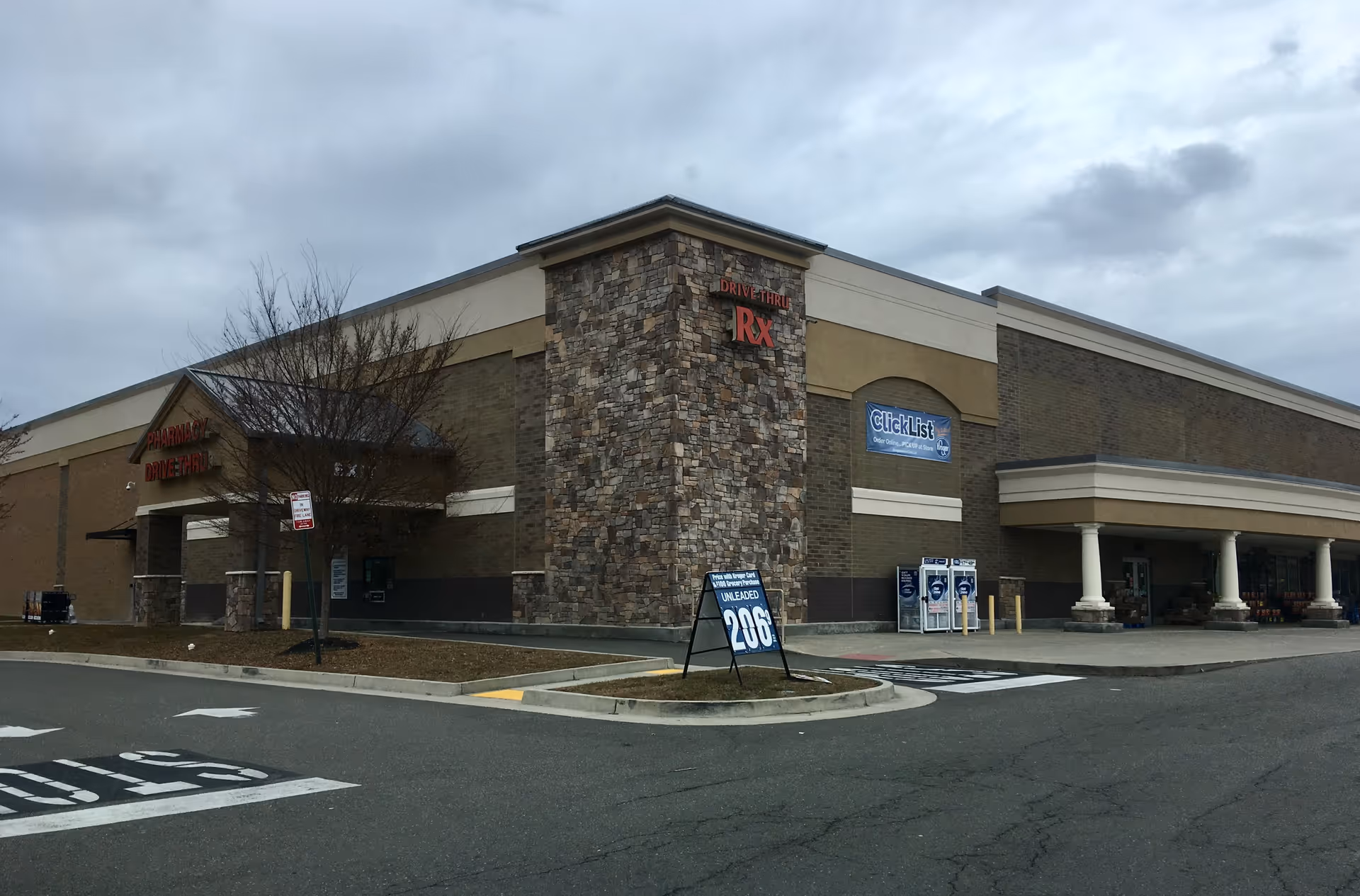 Exterior view of a large shopping center with a Kroger Pharmacy and parking area