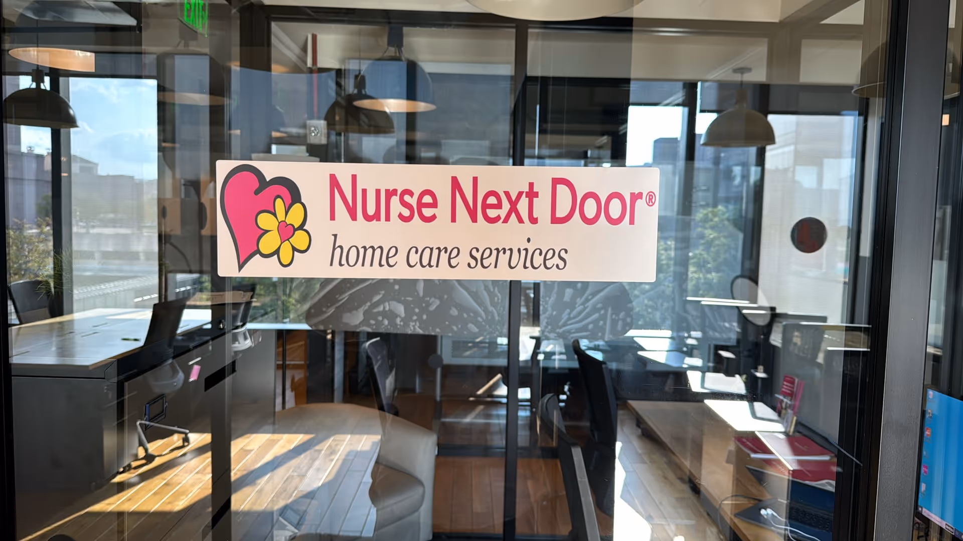 Nurse Next Door sign on glass inside a modern office lobby