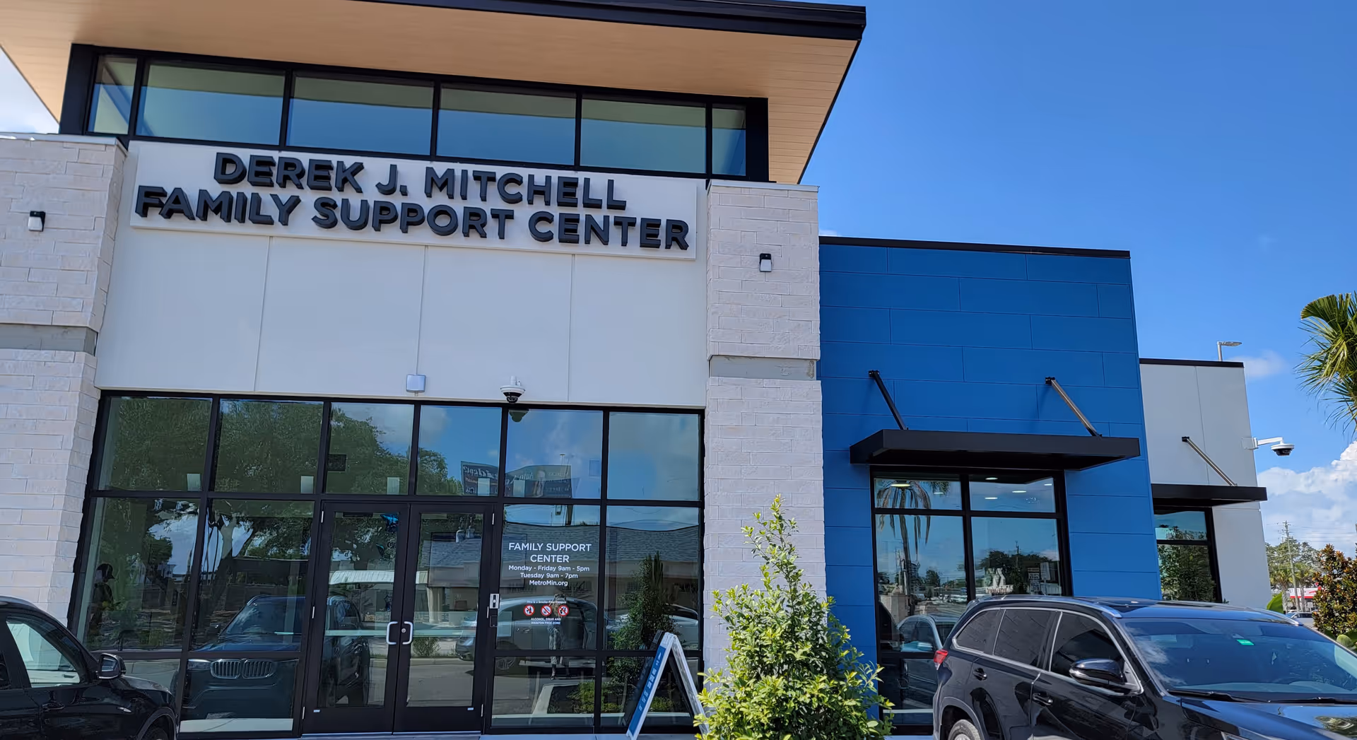 Front view of a building with glass entrance and Derek J. Mitchell Family Support Center sign.