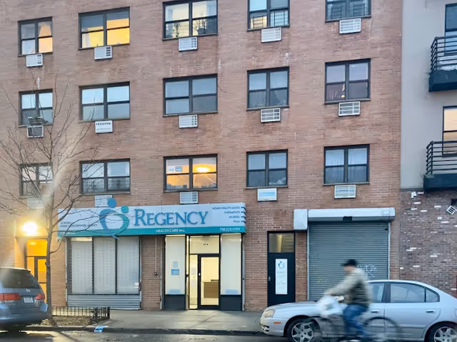 Exterior view of Regency Health Care building with entrance and a passing cyclist.
