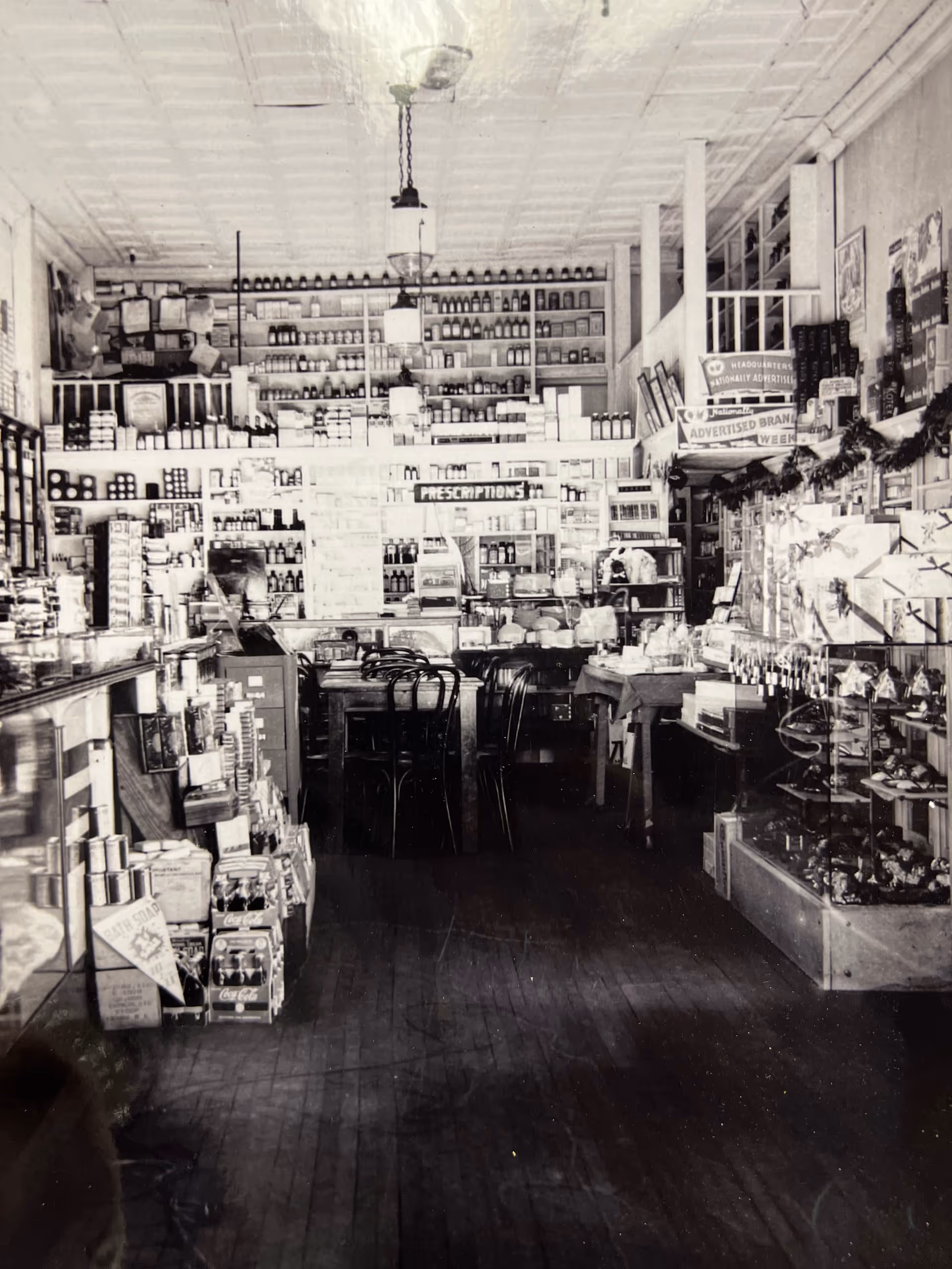 Old-fashioned pharmacy interior with shelves of bottles and a counter in the center.