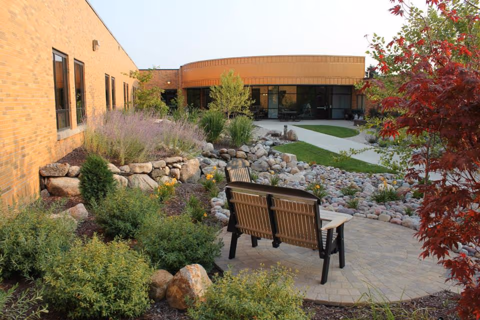 An outdoor courtyard at Burgess Health Center with benches, rocks, and landscaped plants.