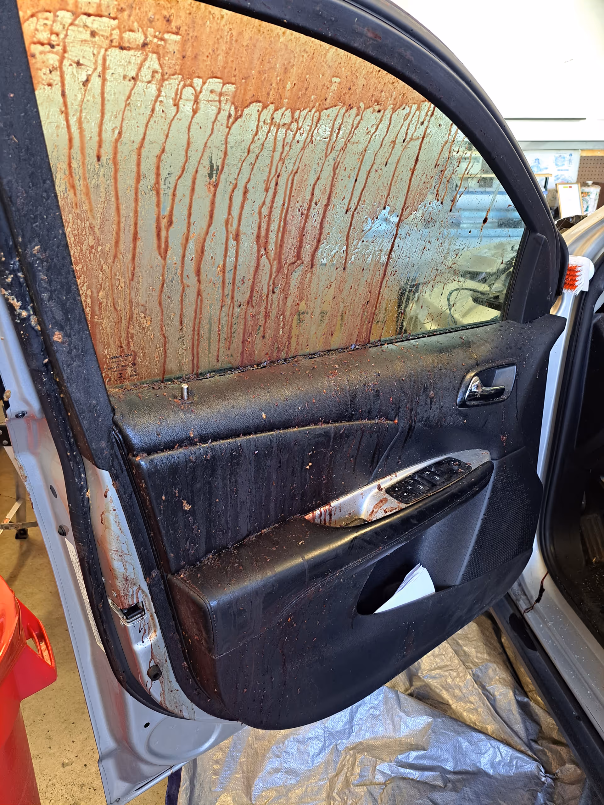 Dirty car door panel and window covered with brownish red liquid streaks.