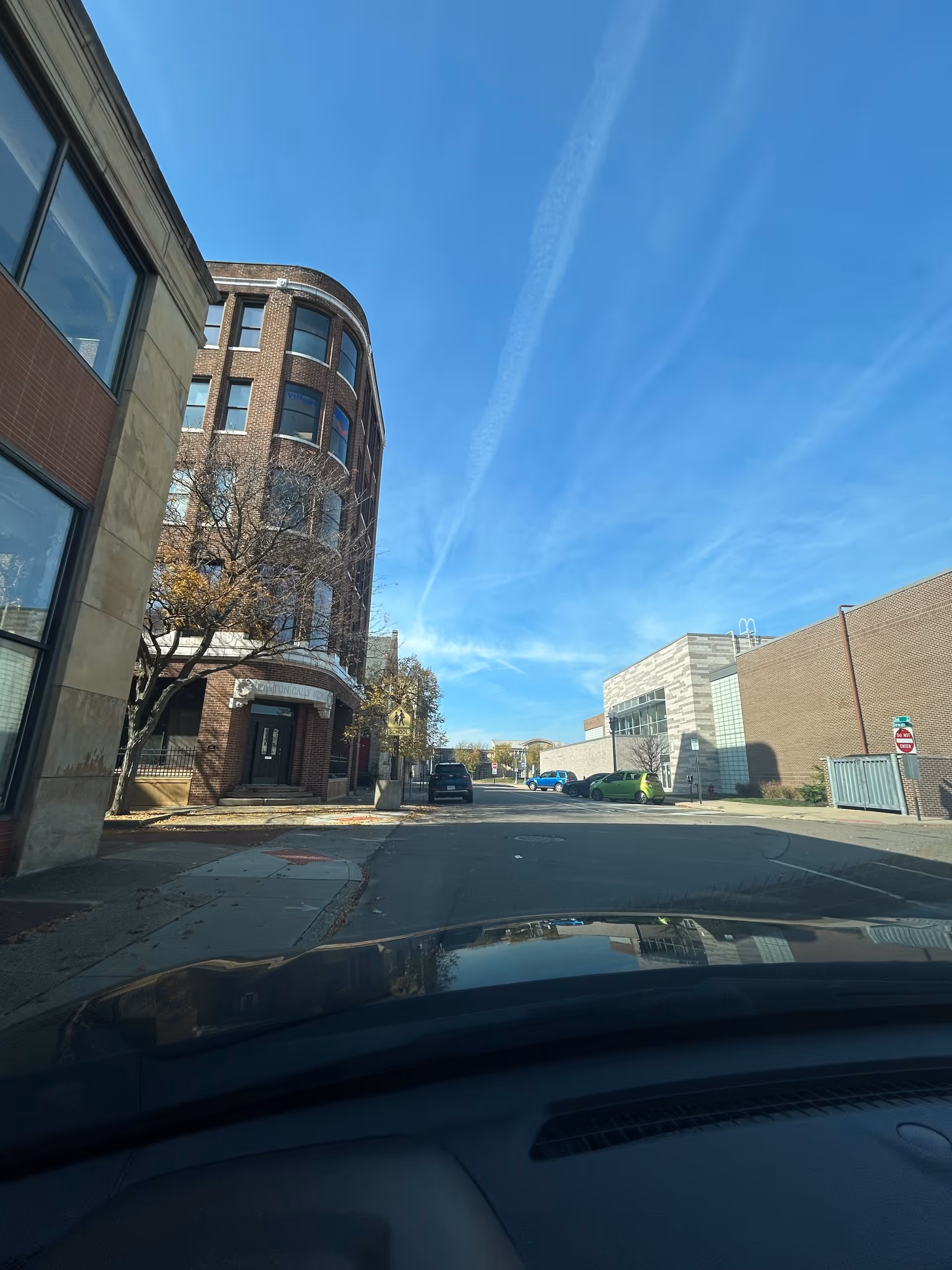 Street view of a curved brick senior living building under a blue sky.