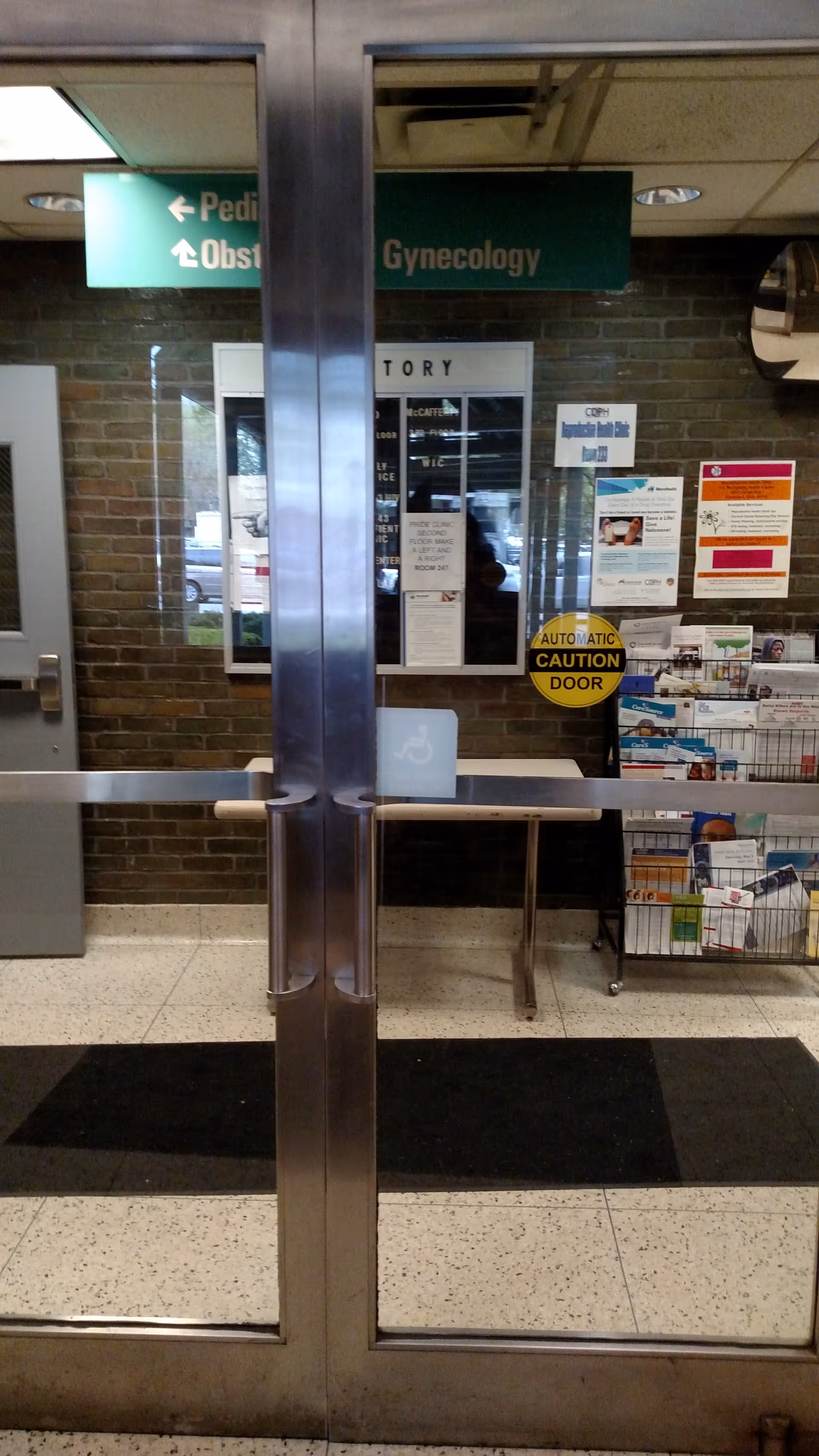 Hospital lobby with automatic glass doors, signage, and a brochure rack.