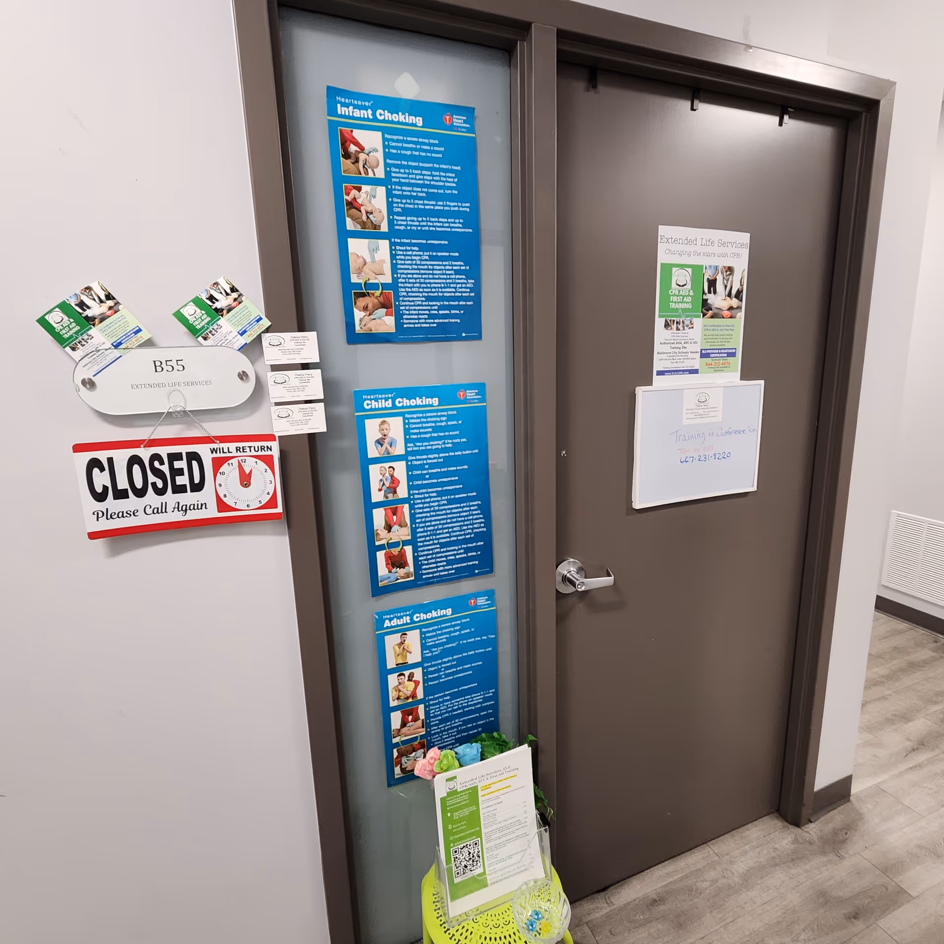 Interior hallway with a closed door covered in safety posters and signs.