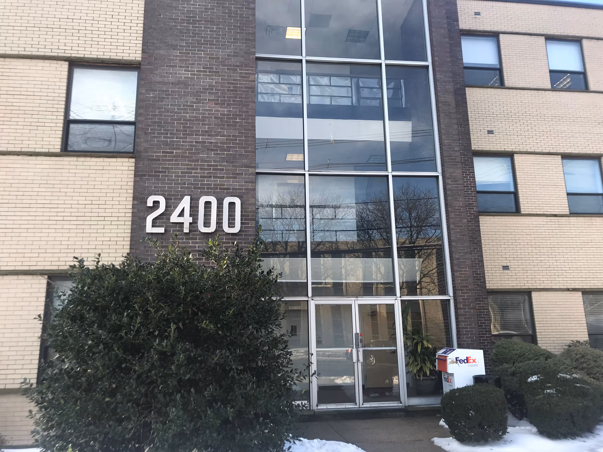 Facade of a modern, multi-story building with a large glass entrance and 2400.