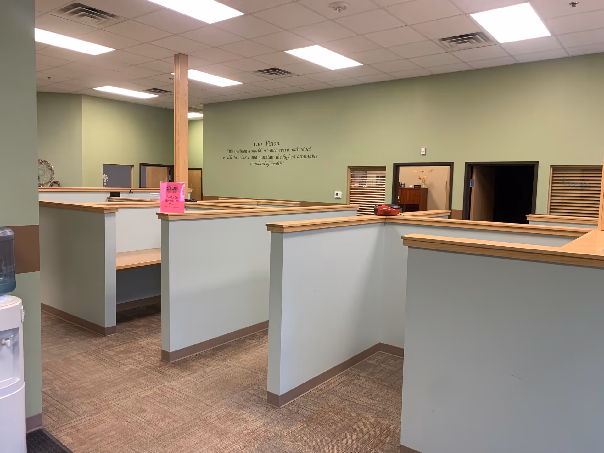 Green-walled interior featuring cubicles, desks, and a reception-like service area.