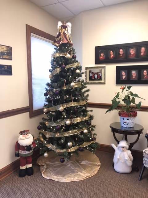 Interior of a senior living facility lobby featuring a Christmas tree and framed photos.
