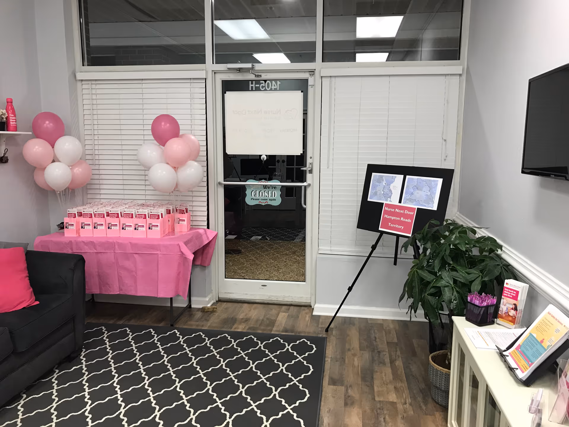 Lobby area featuring pink decorations, brochures, a sofa, and a glass door.