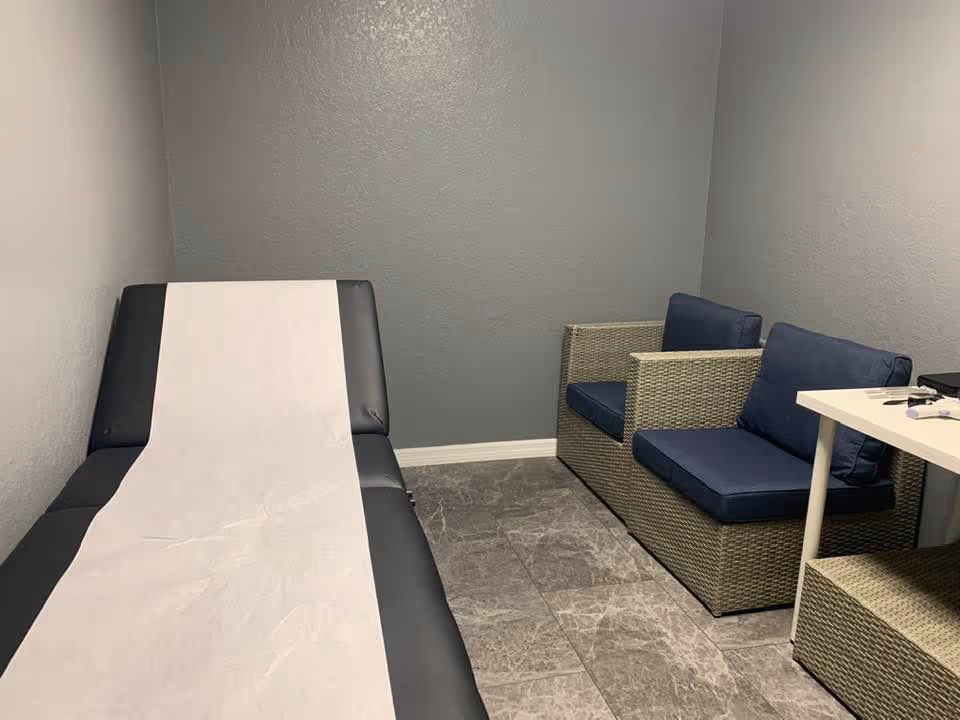 Small interior room with an exam couch covered by paper and wicker seating along the wall.