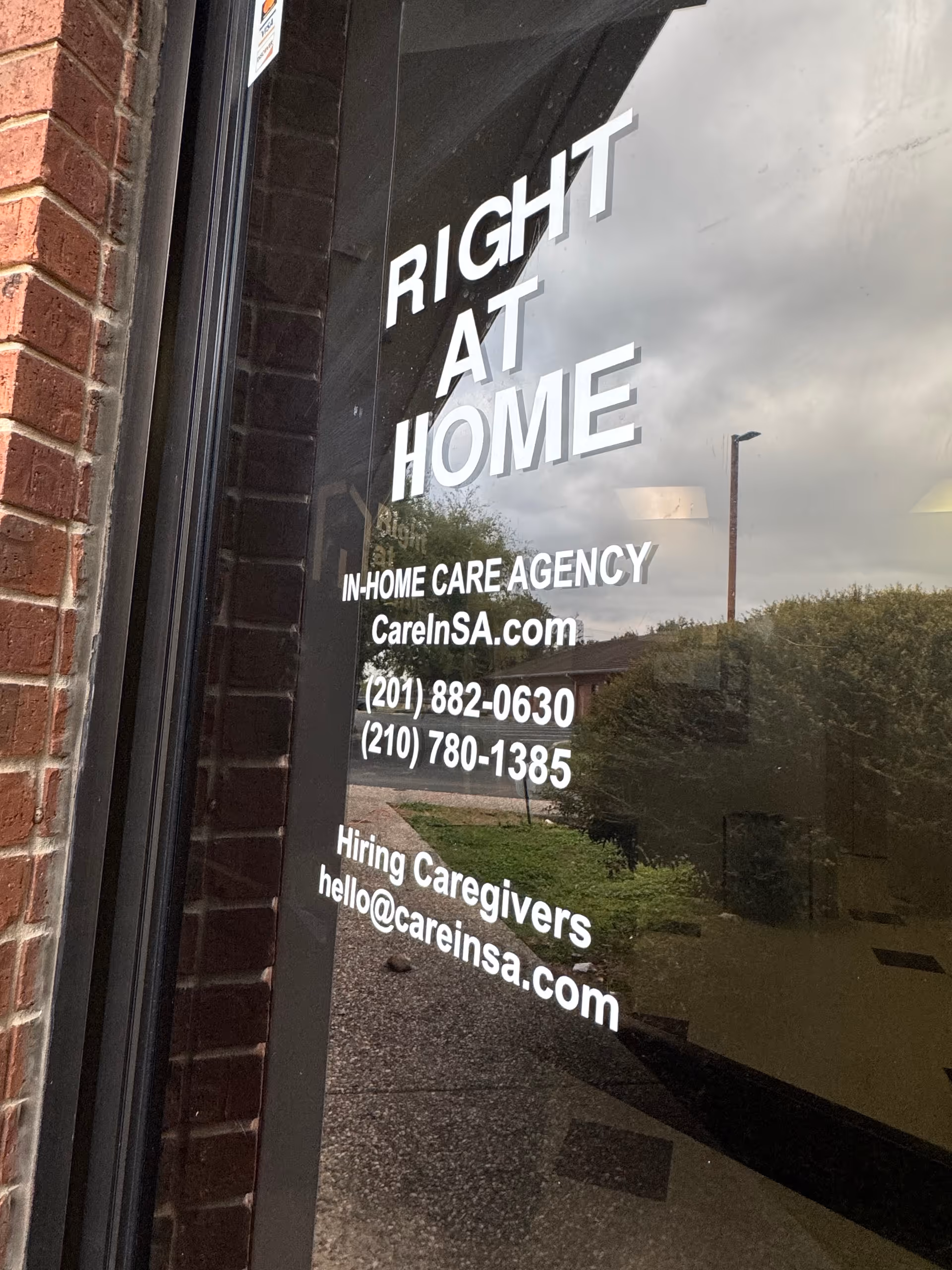 Glass storefront displaying 'Right at Home' signage and contact details on a brick exterior